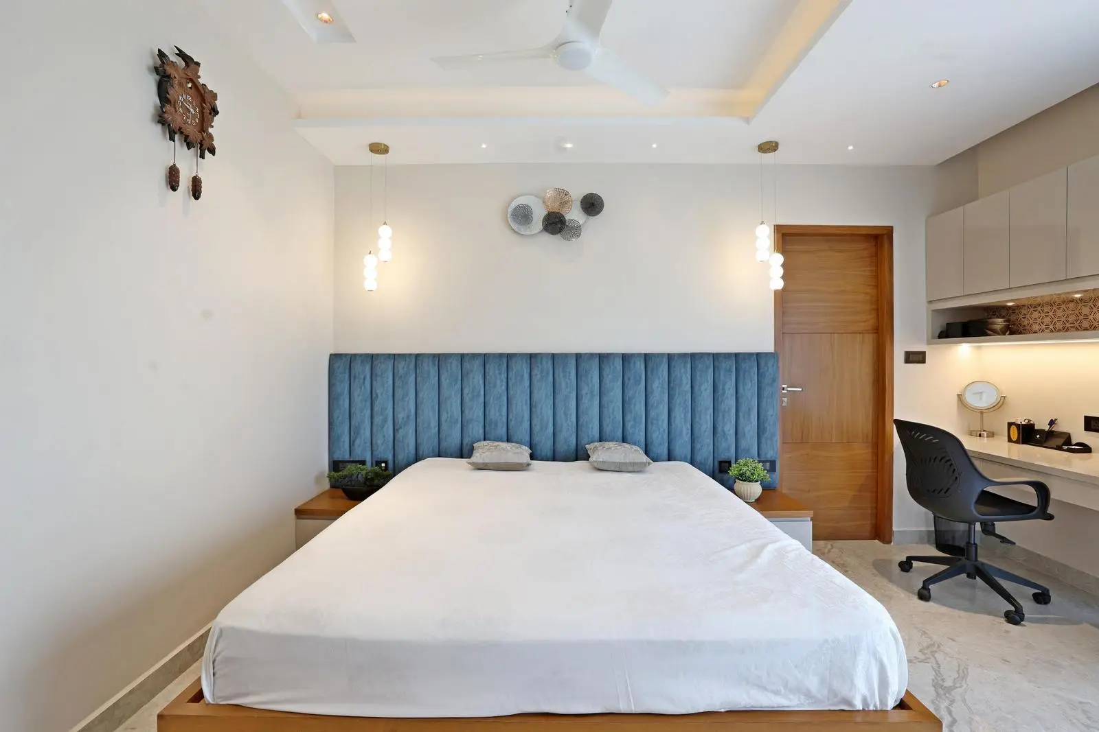 Master Bedroom 4 has a central bed and a study corner by the window. Whites, warm wood, and deep blue create a balanced palette. Recessed lighting and minimalist furniture ensure a modern, functional, and elegant space.