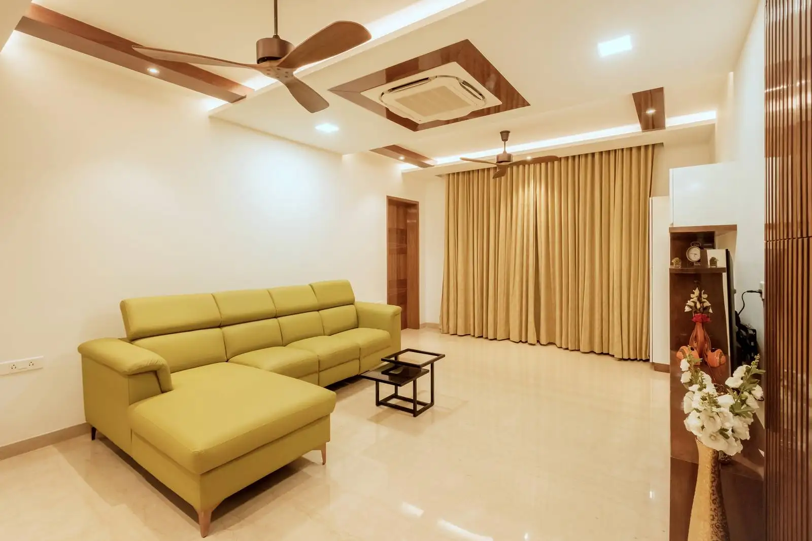 The flooring is polished, light-colored marble, which enhances the brightness and luxury of the space. The glass doors provide access to a balcony, enhancing the connection between indoor and outdoor spaces.