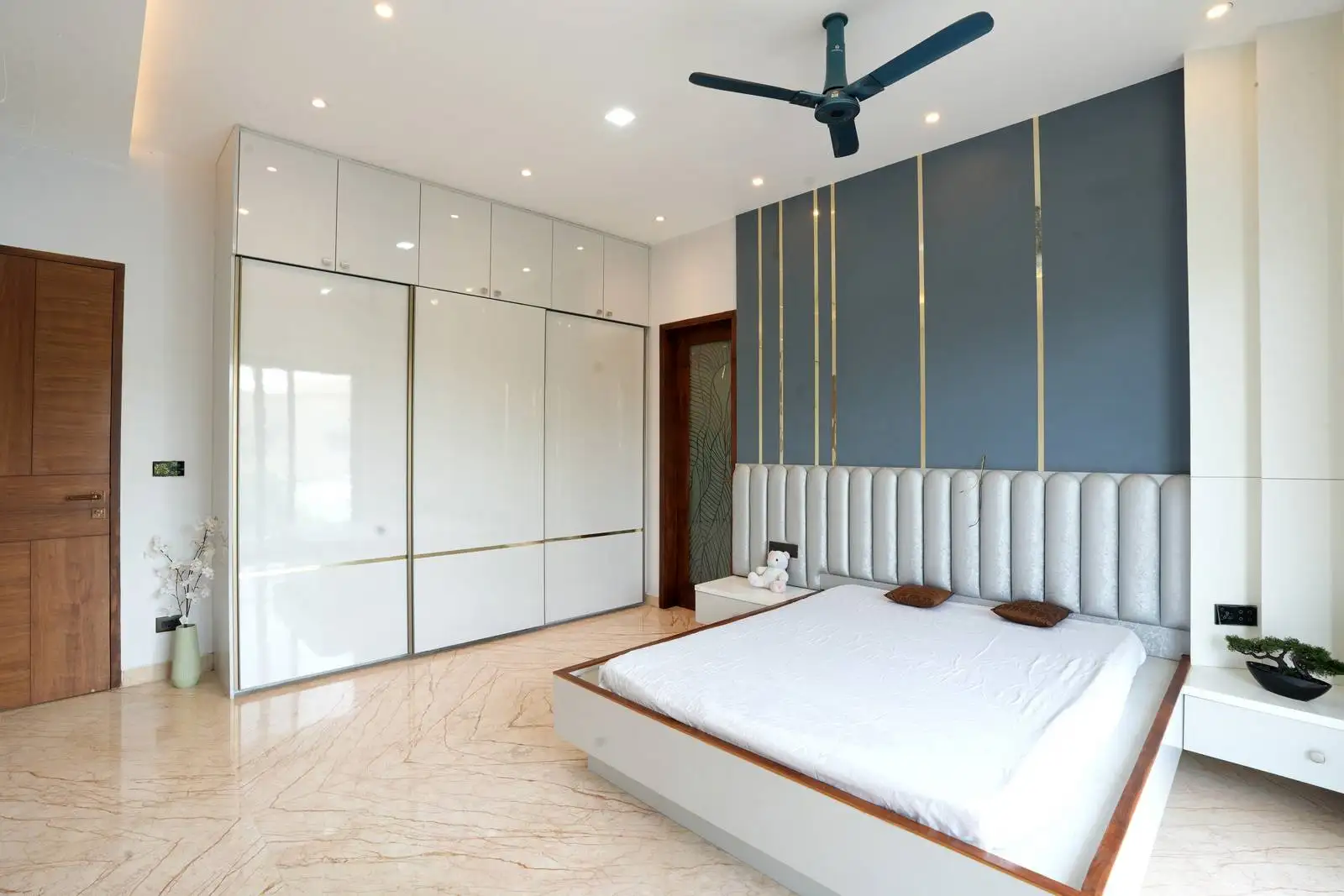 Polished marble flooring adds elegance and brightness, while a large white wardrobe with gold trim offers stylish, functional storage.