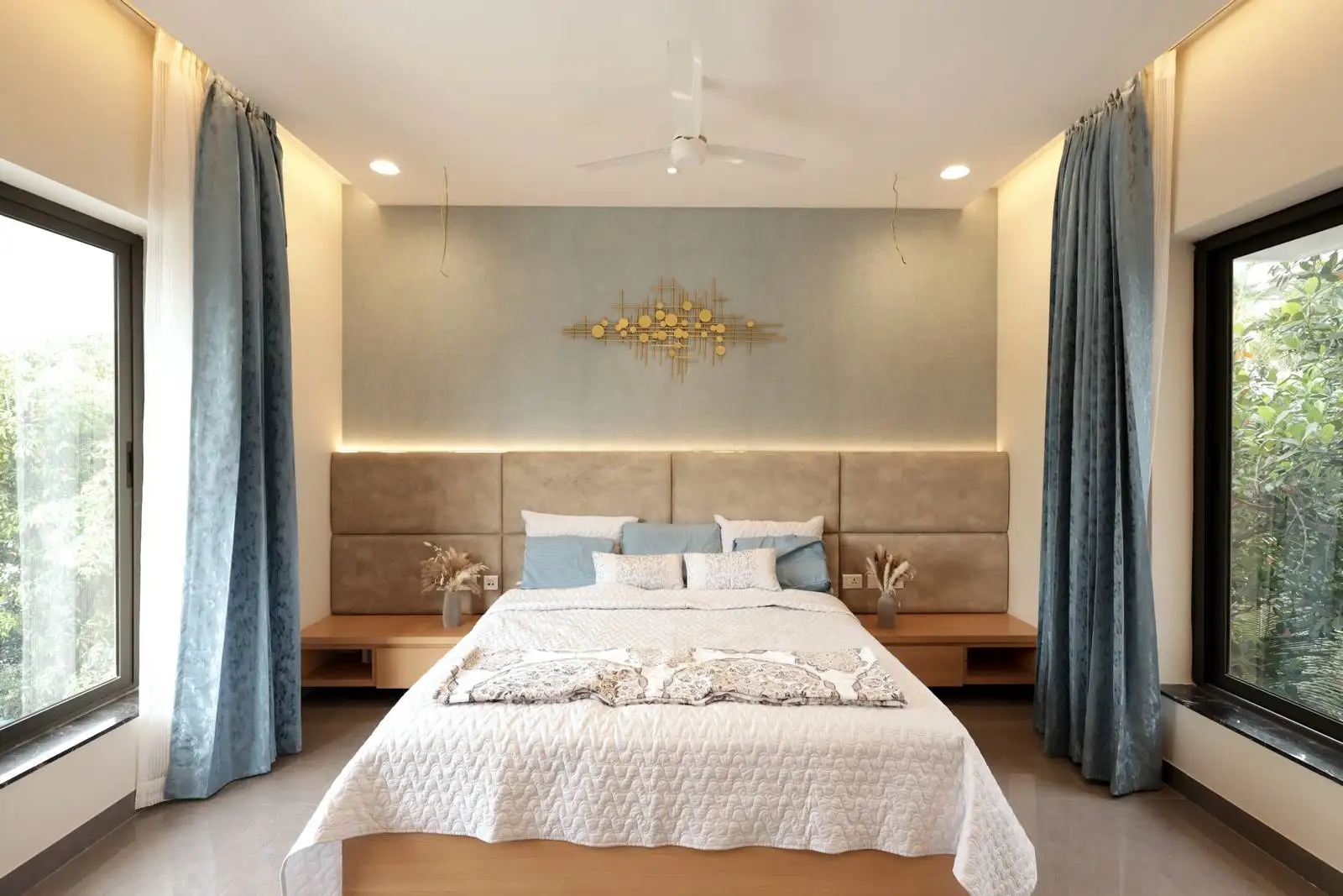 The bedroom is symmetrically designed, with the bed as the central focal point.
Large windows on both sides of the bed allow abundant natural light and offer views of greenery, creating a serene and airy atmosphere.