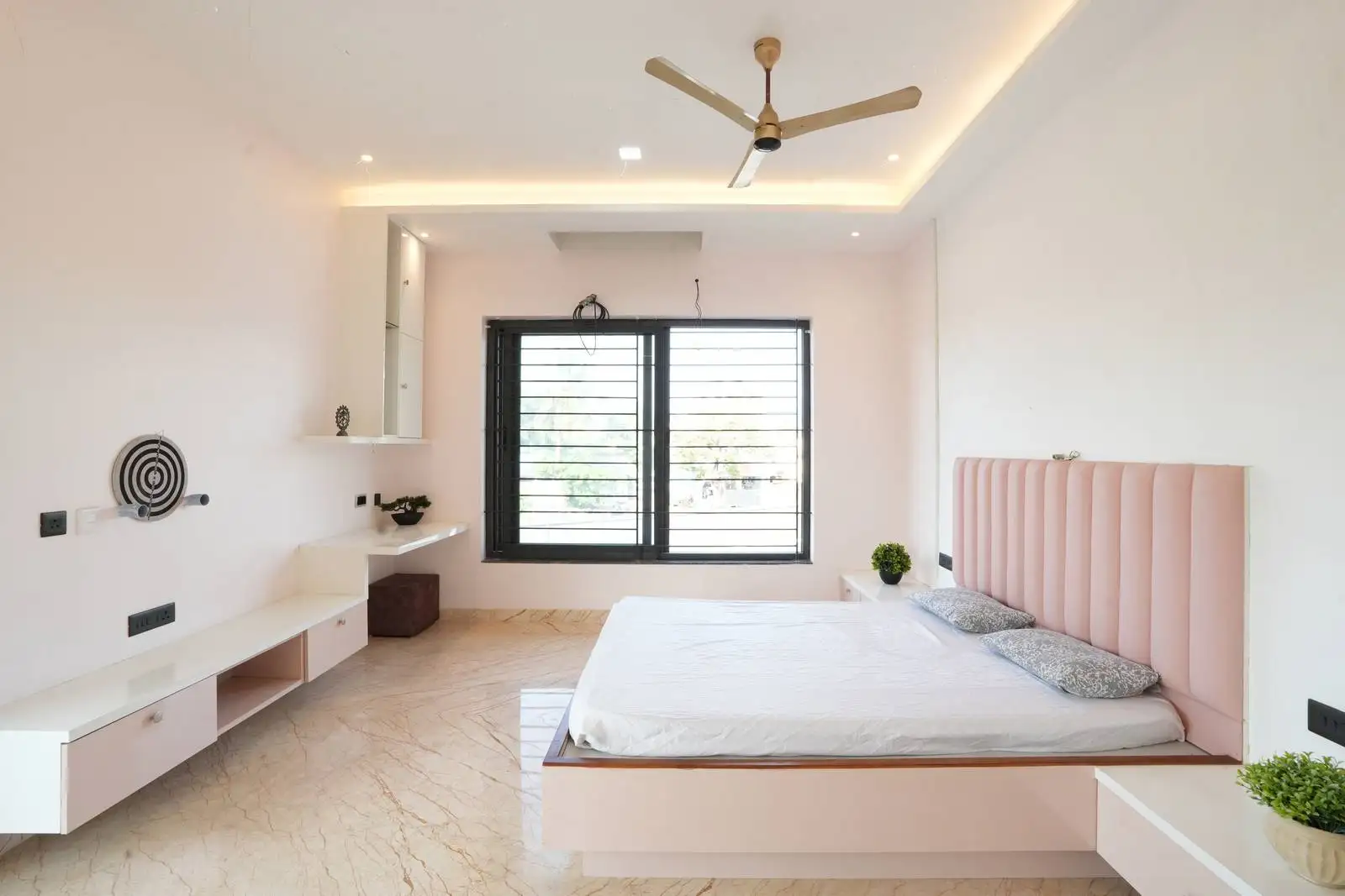 Recessed lighting and a ceiling fan ensure comfort and brightness, while soft-toned walls and a dark wood door with frosted glass add contrast and elegance.