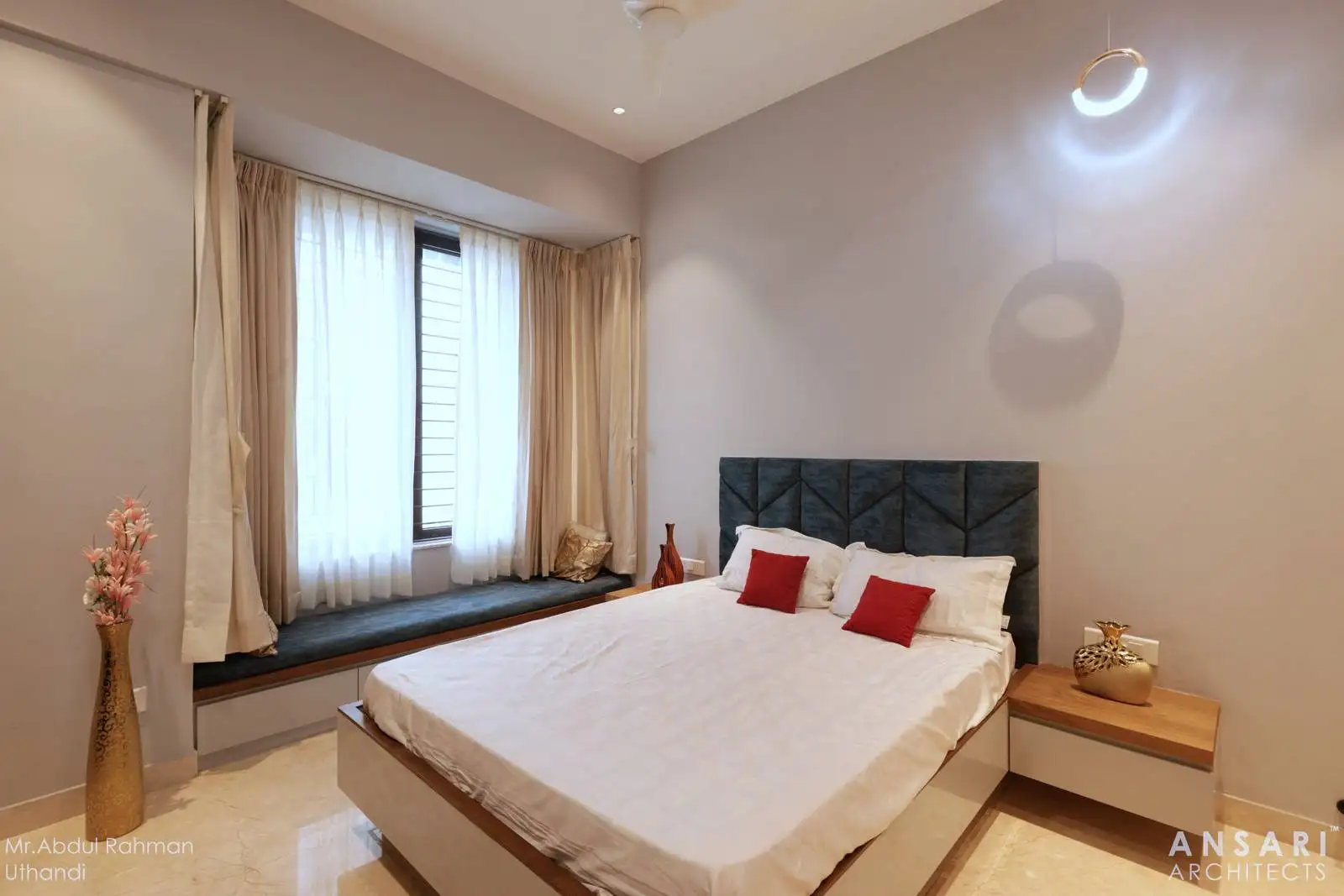 A minimalist bedroom with a centrally placed bed and a built-in window seat, creating a bright, cozy nook for relaxation and reading.