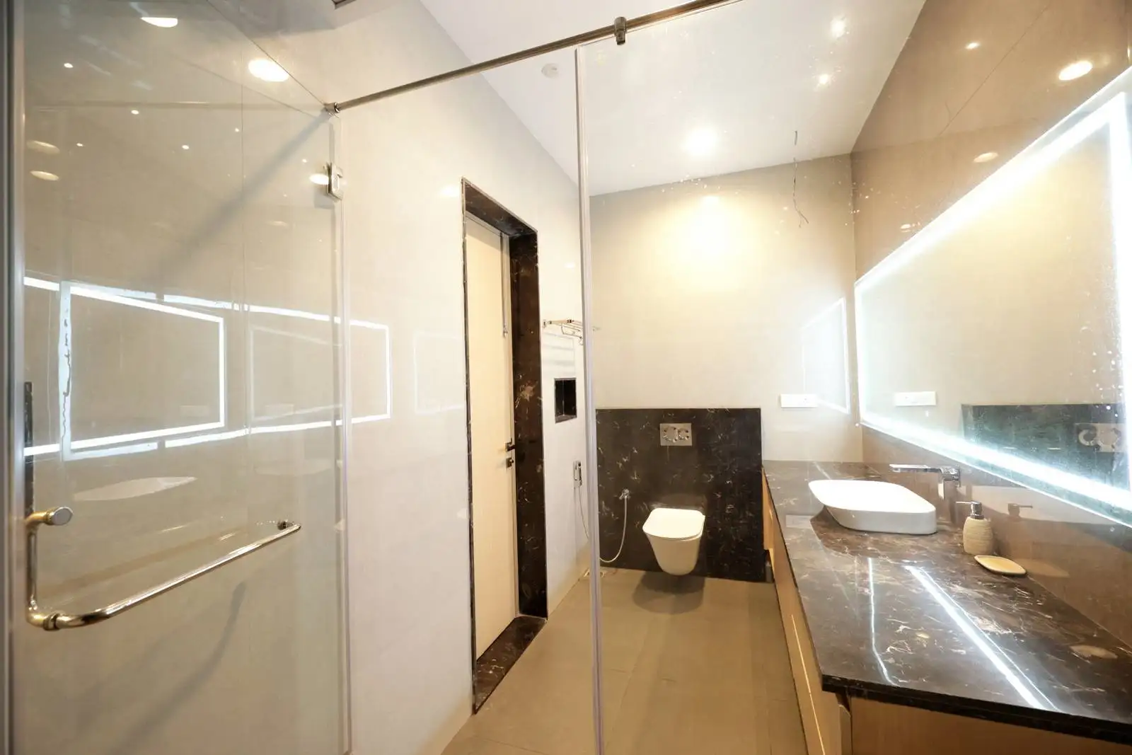 The bathroom features a linear, elongated layout, maximizing the use of available space.
The shower area is enclosed with a clear glass partition, visually expanding the space and maintaining an open, airy feel.