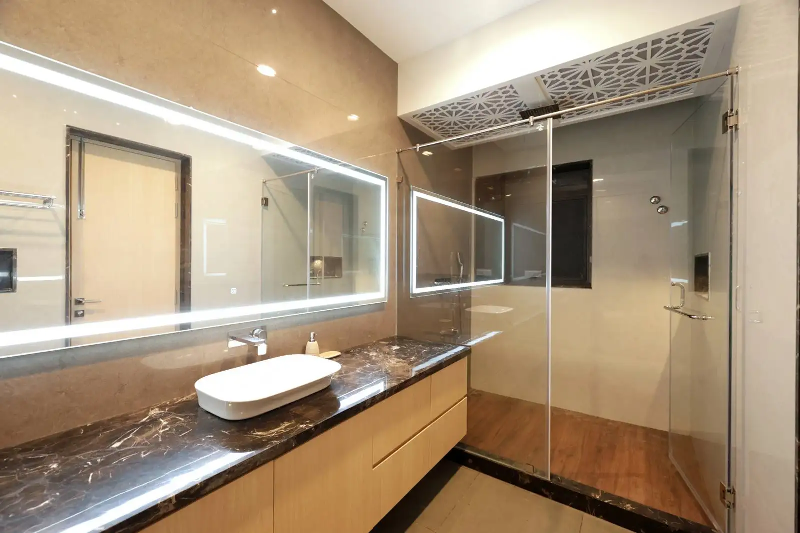 The bathroom features a rich dark marble vanity, light wood cabinetry, and glossy tiled walls, with wood-finish shower flooring adding natural warmth to the elegant, spa-like space.