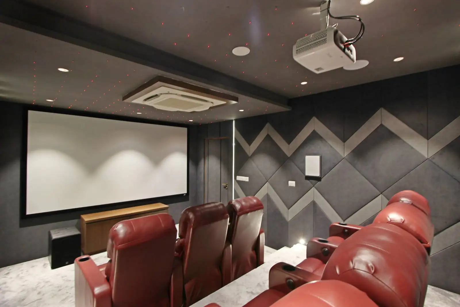 The home theater features seats with armrests and cup holders for comfort, and is wired for surround sound with wall-mounted speakers for an immersive experience.