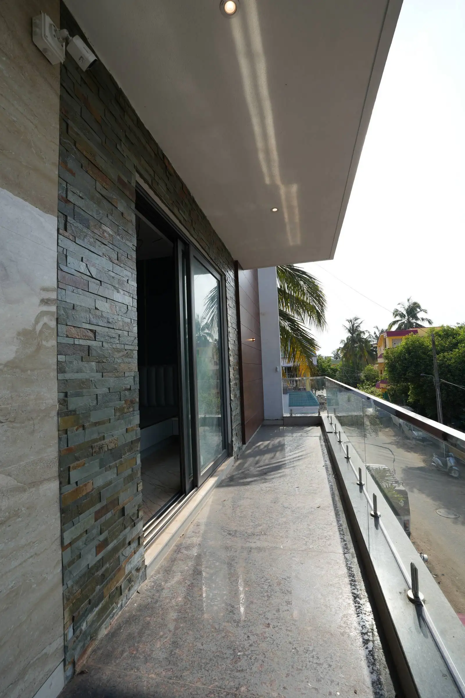 The balcony combines stone and wood panels with glass railings, seamlessly connecting indoor and outdoor living spaces.