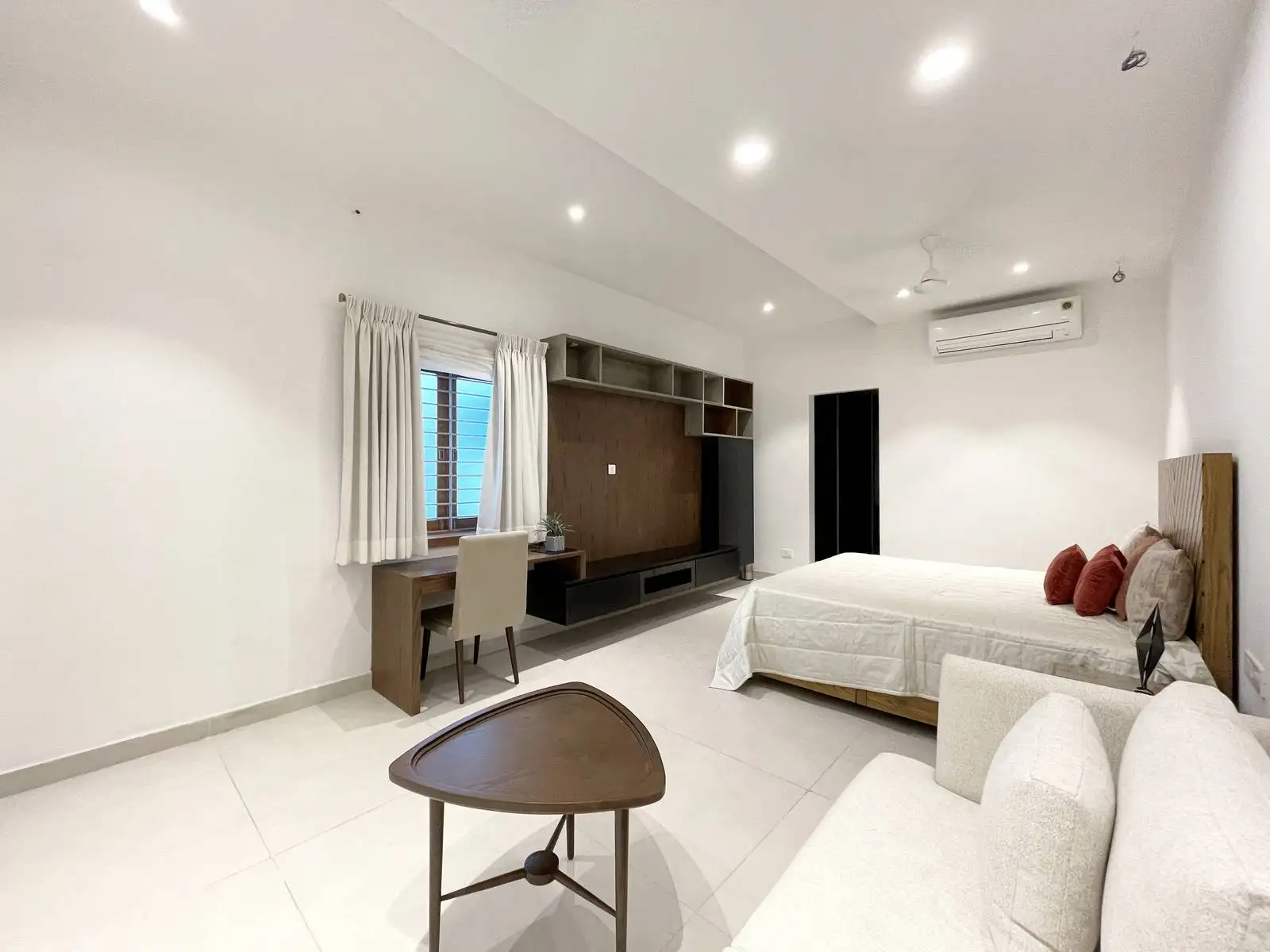 This bedroom study area features a custom-built desk with dark wood and matte laminate shelving, positioned by the window for natural light. The design combines functionality and minimalist clarity, enhancing focus and spatial openness.