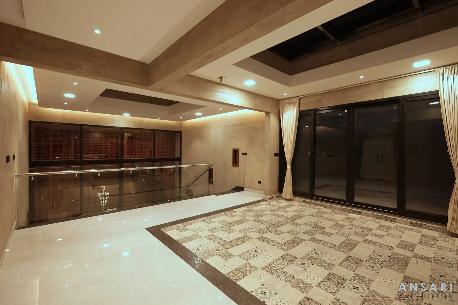 Second-floor entrance with beige interiors, patterned tile flooring, large glass windows to the terrace, and sliding doors overlooking a double-height space with a chandelier.