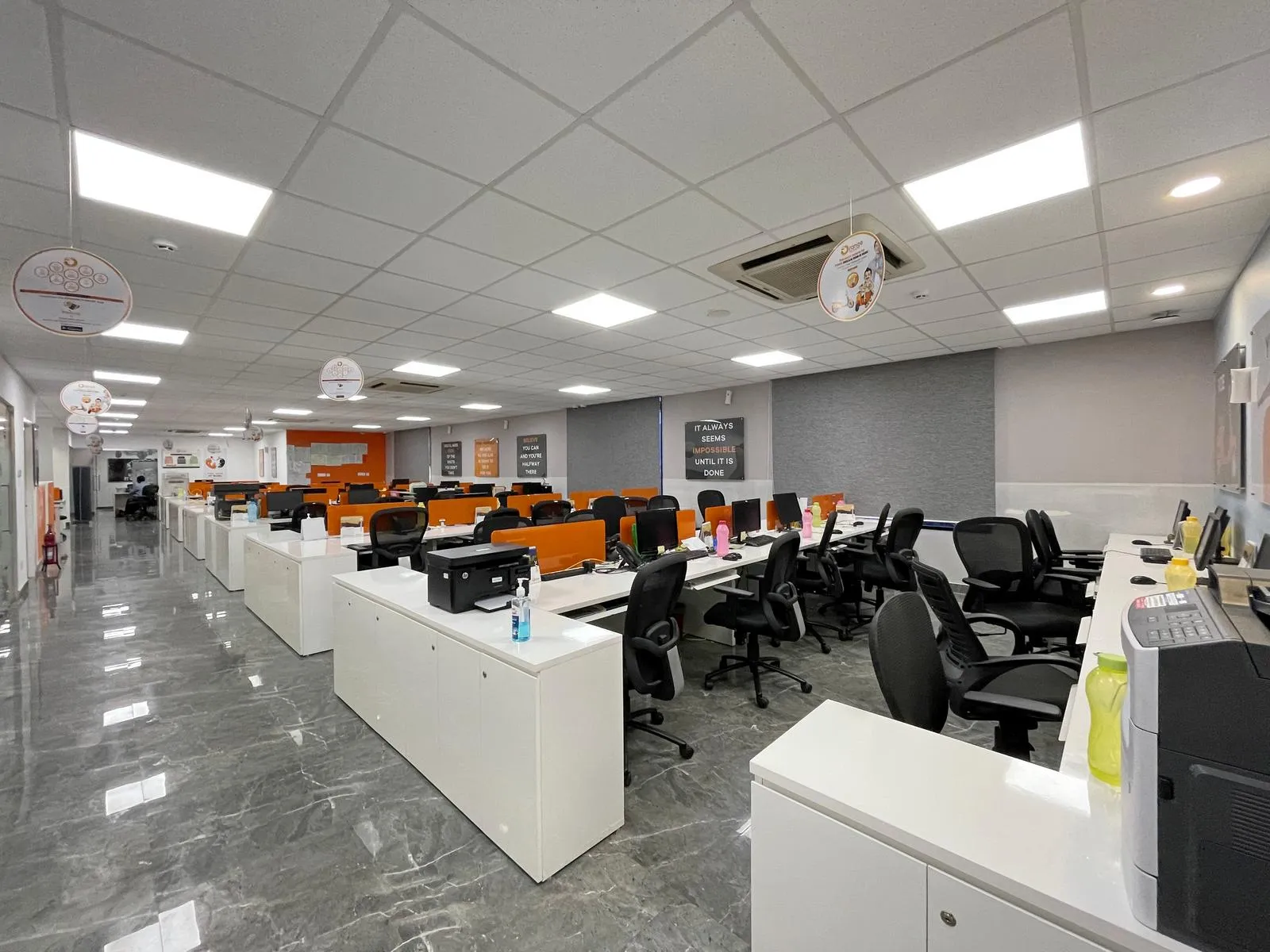 The first-floor workstation accommodates 63 seats within an open-plan layout that promotes collaboration while maintaining defined work zones. Along the central spine, low-height white storage cabinets act as subtle dividers while providing ample storage, supported by overhead and side units that ensure easy access without visual clutter.