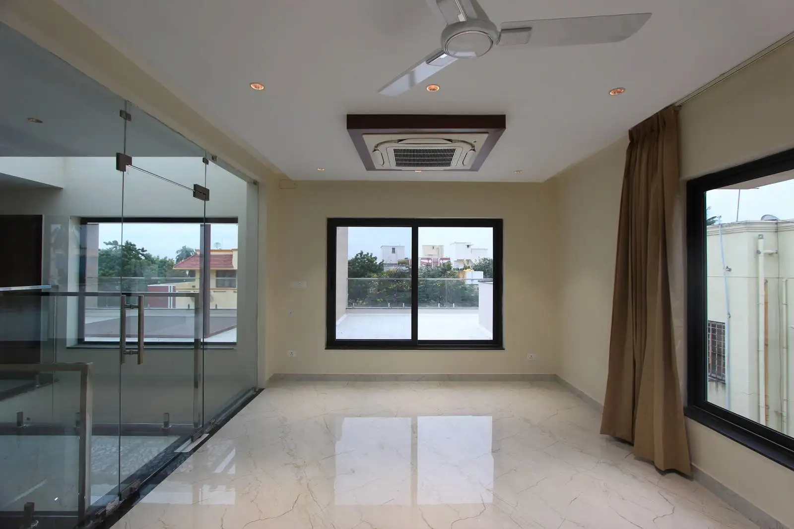 The room features large black-framed windows that connect indoors with outdoors, complemented by polished marble flooring for a sleek, durable finish.