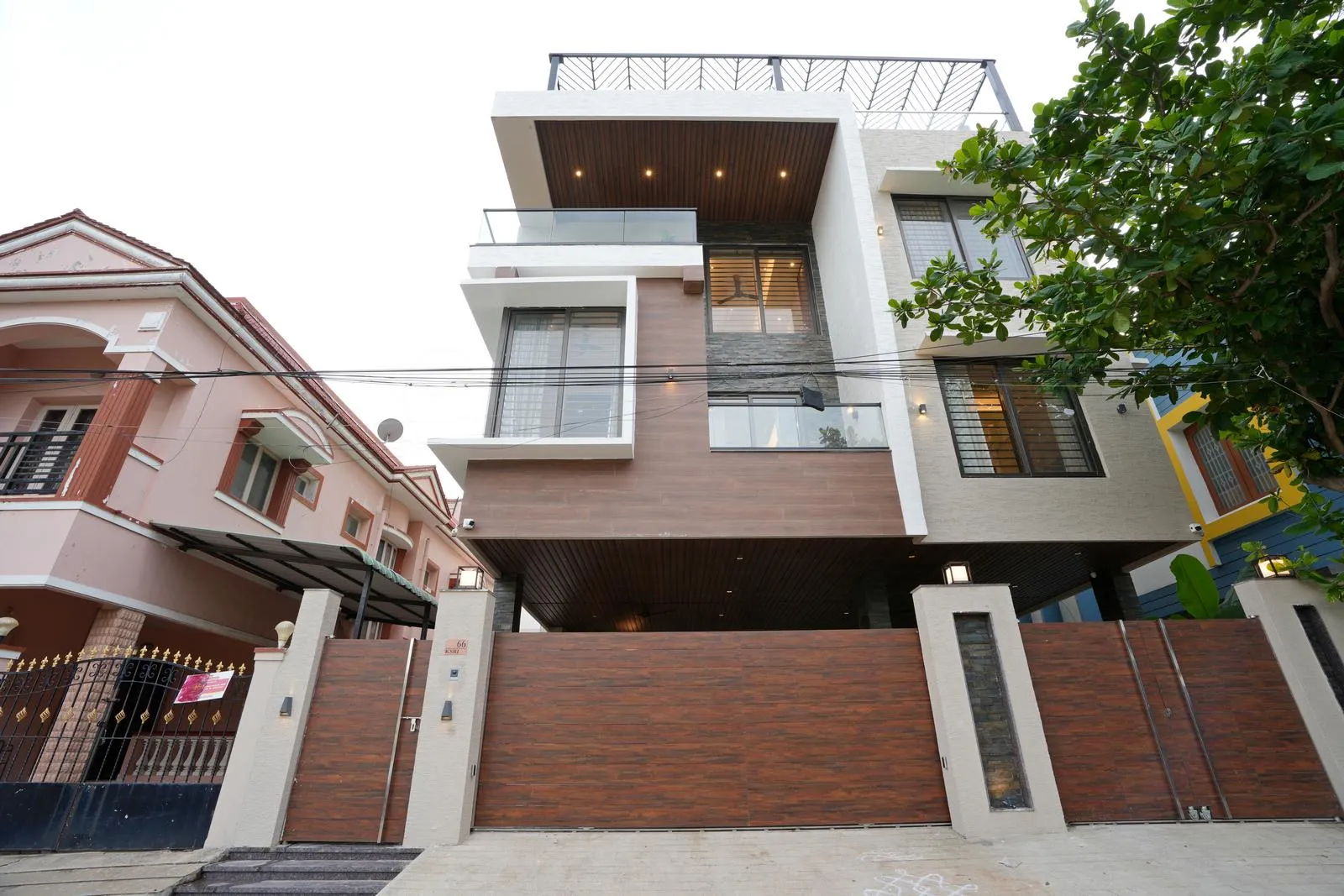 The house features interlocking volumes with cantilevered projections, combining wood, plaster, and glass finishes for a modern, dynamic facade.