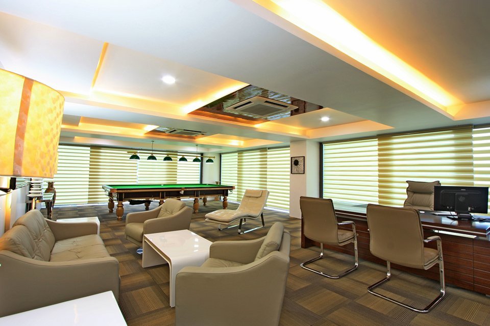 Room with plush leather seating, a sleek pool table, and large windows with blinds for natural light and privacy control.