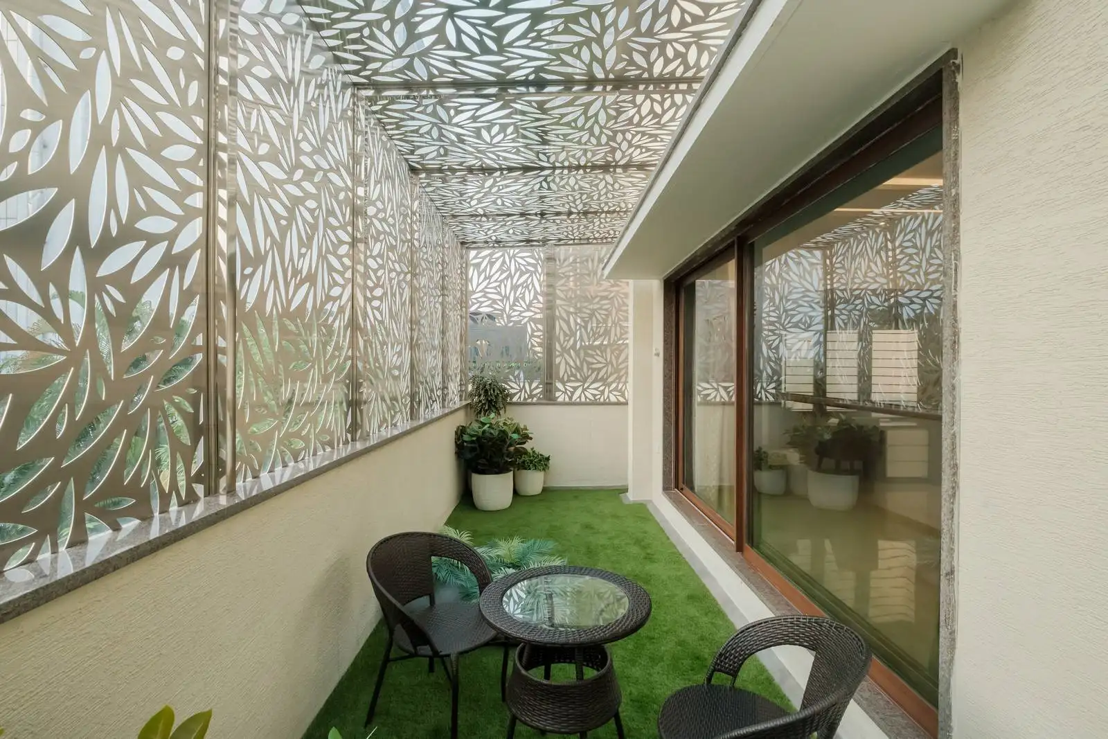 A private balcony space with green turf flooring and screening elements offers a garden-like retreat, ideal for relaxation in dense urban settings.