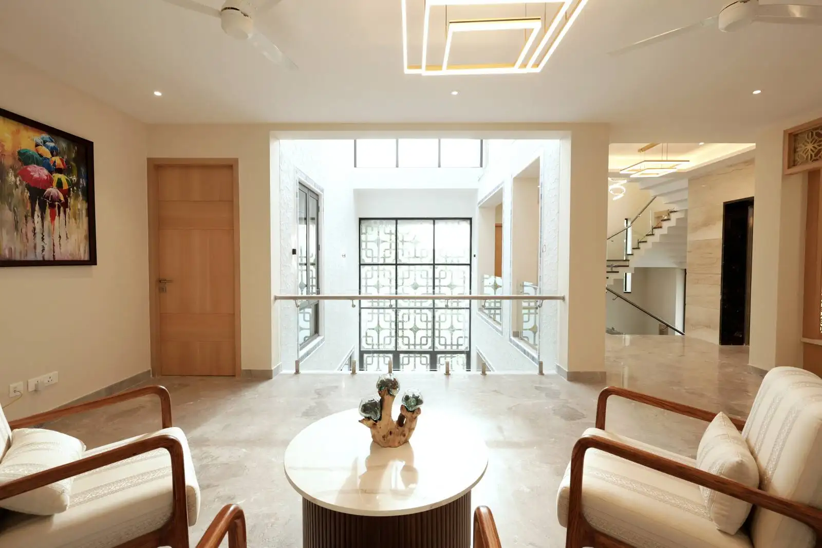 The space is visually connected to the lower floor via a glass and metal railing, enhancing openness and allowing natural light to flow between levels.