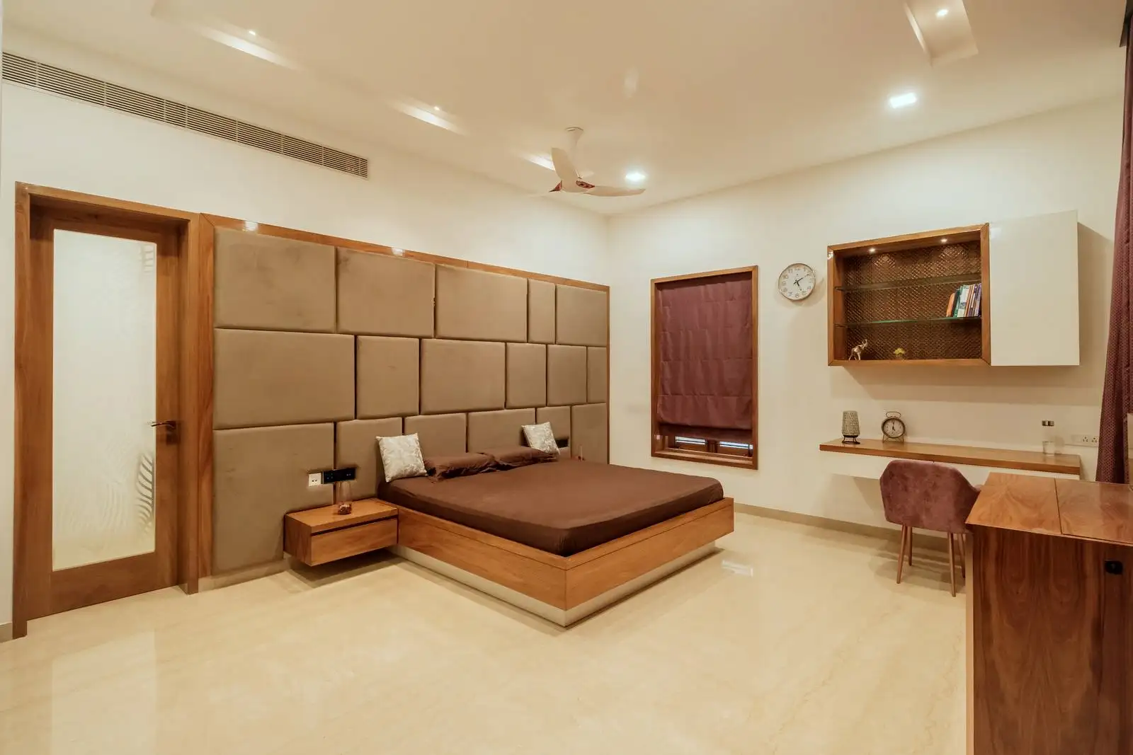 A warm and cohesive bedroom interior featuring polished light-toned flooring and a padded headboard wall for added comfort and elegance.