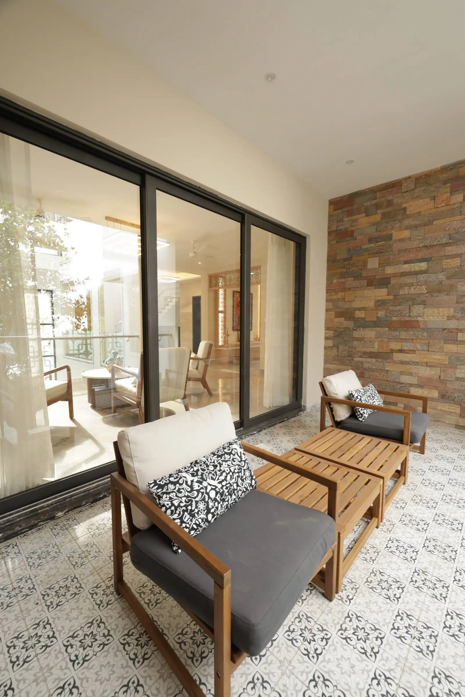Large sliding glass doors provide a strong visual and physical connection between the indoor sitout area and the balcony, allowing for flexible use and an extended living space.