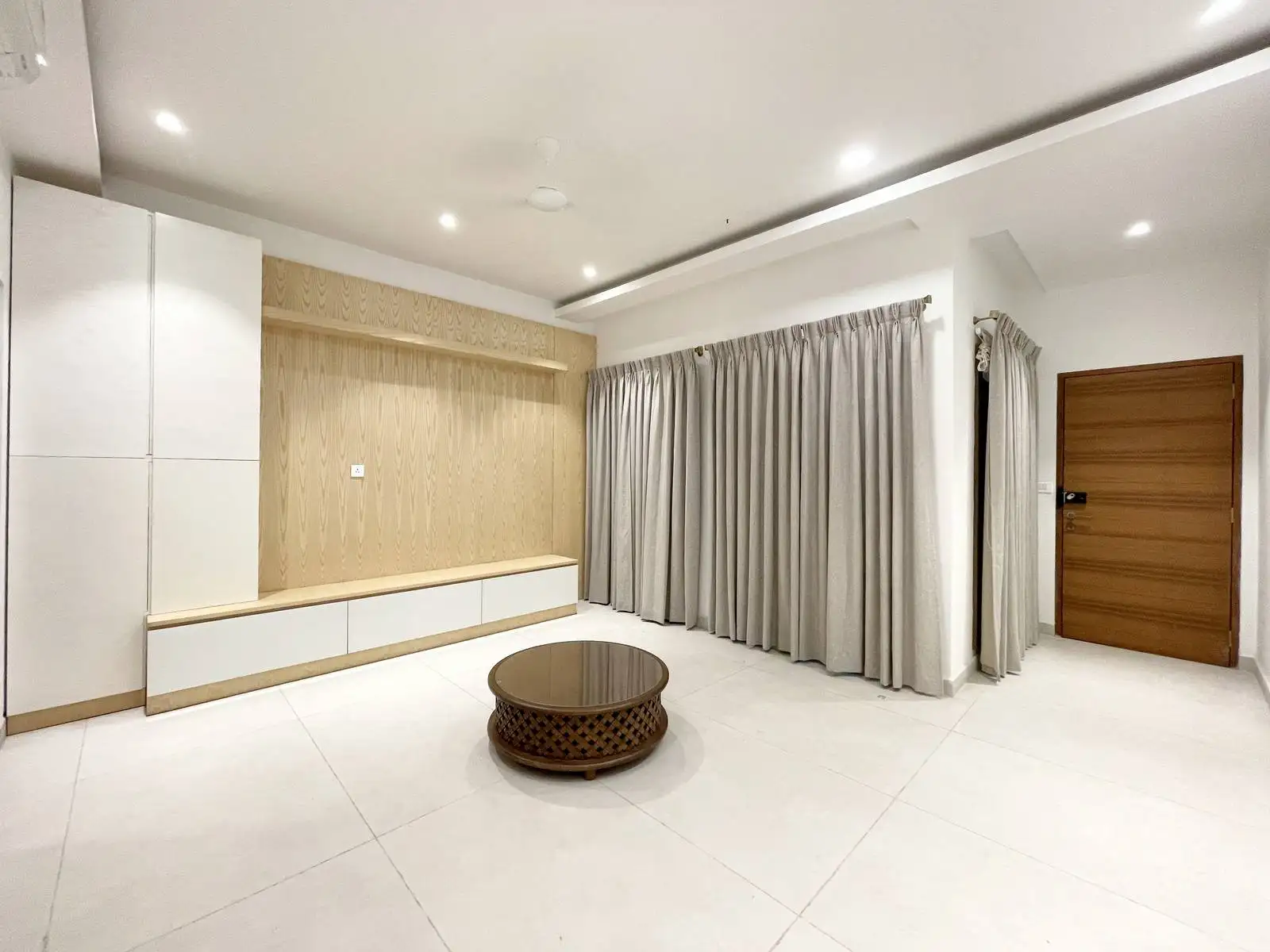 The multipurpose hall has an open, flexible layout with integrated storage, vertical timber accents, and neutral tones. Minimalist detailing and layered lighting enhance comfort, versatility, and visual clarity.