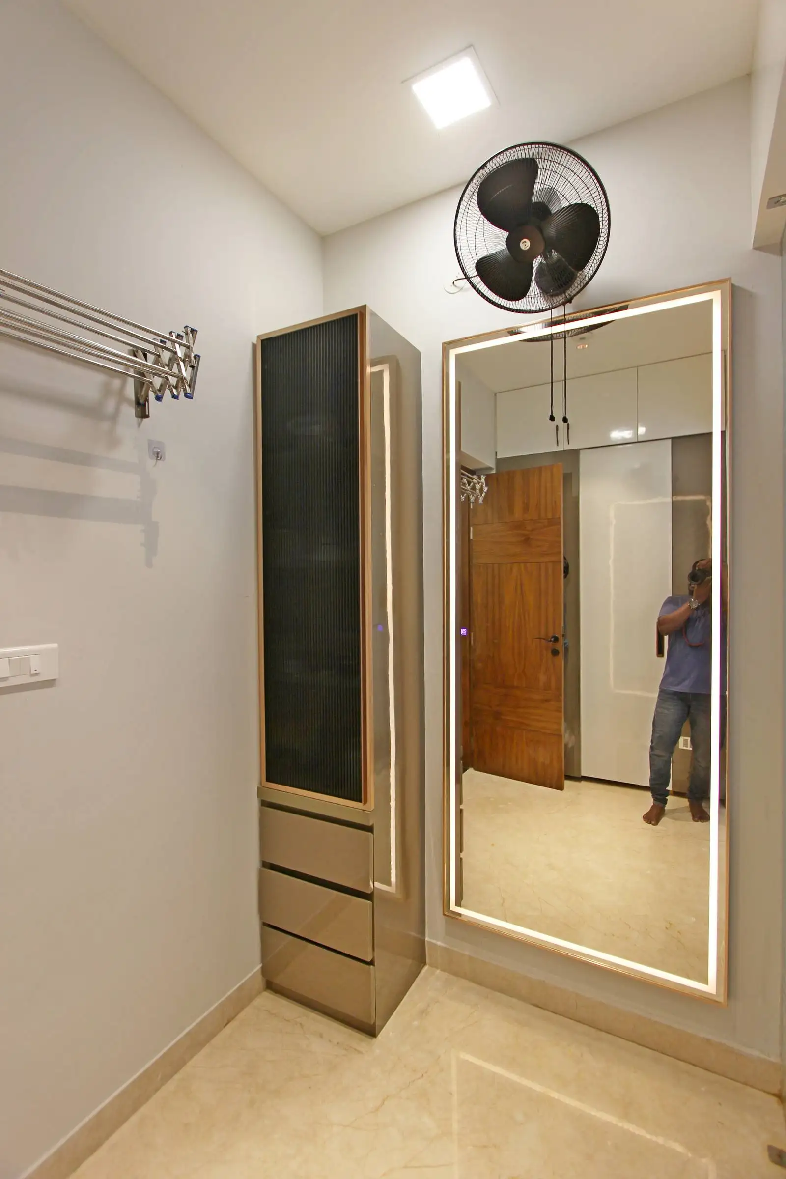 The LED-lit mirror offers excellent task lighting for dressing and grooming, eliminating shadows and enhancing visibility. A wall-mounted fan ensures ventilation and comfort, especially in a compact space.
