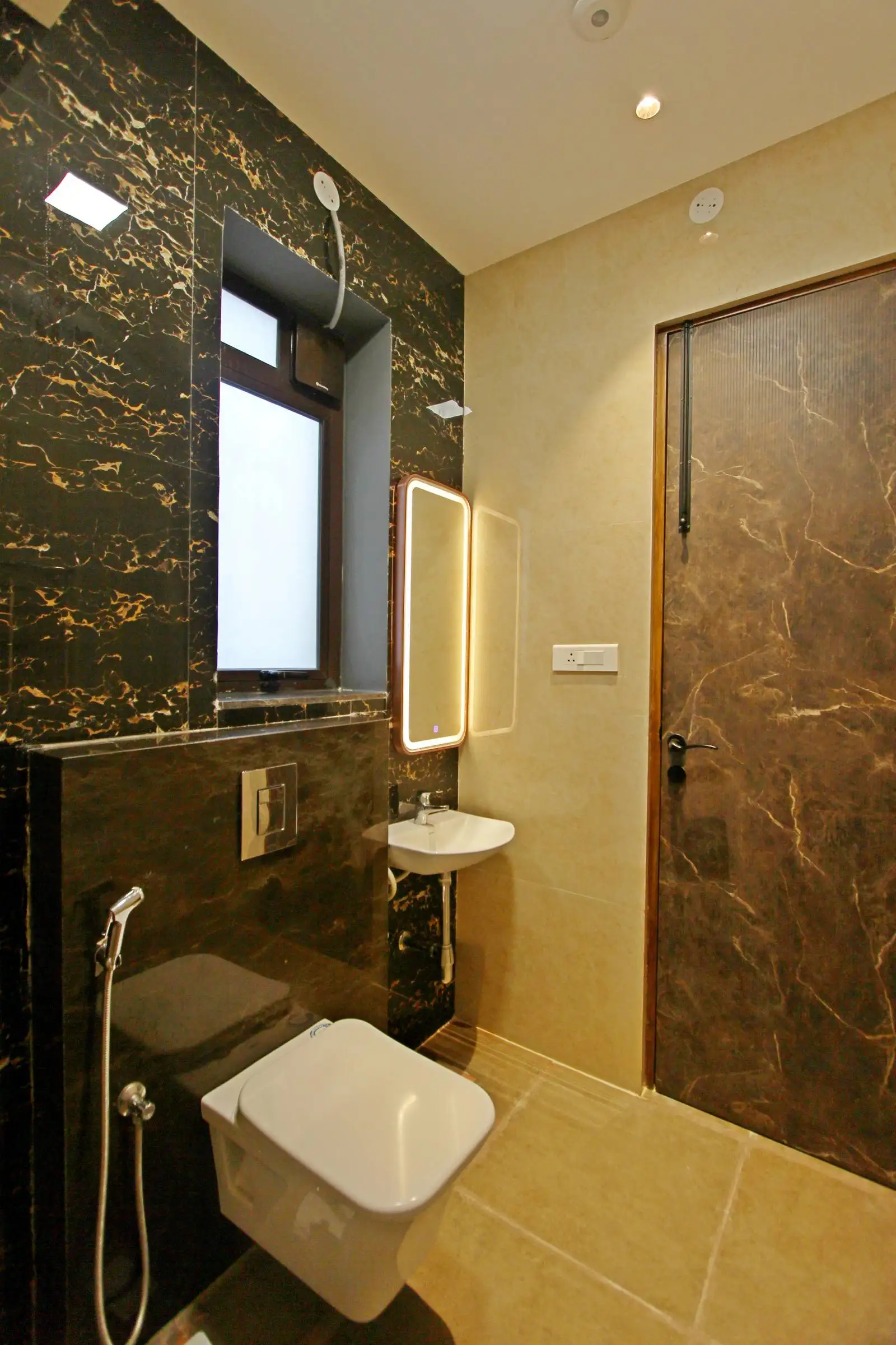 A stylish bathroom featuring a wall-mounted toilet, sleek sink, illuminated mirror, and contrasting wall and floor finishes, combining elegance and functionality.