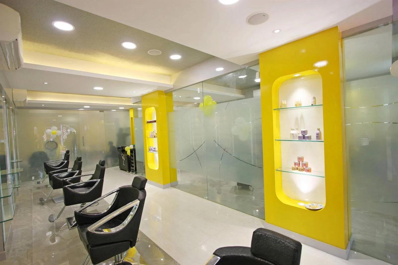 Beige vitrified flooring and a gypsum ceiling with recessed and cove lighting brighten the space and enhance clarity. Frosted glass partitions with aluminum frames define zones while maintaining transparency and light flow.