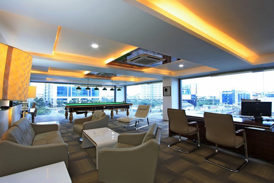 Layered ceiling with cove lighting and recessed spotlights creates a warm, functional space. Floor-to-ceiling windows with built-in blinds offer panoramic views and light control.