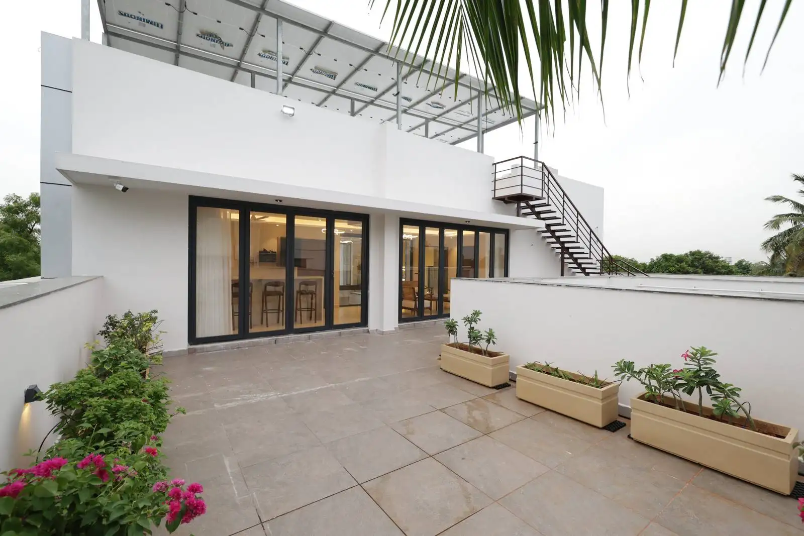 Large sliding glass doors provide seamless access from the interior, visually connecting the indoor and outdoor areas. The terrace is bordered by low parapet walls, ensuring safety while maintaining open views.