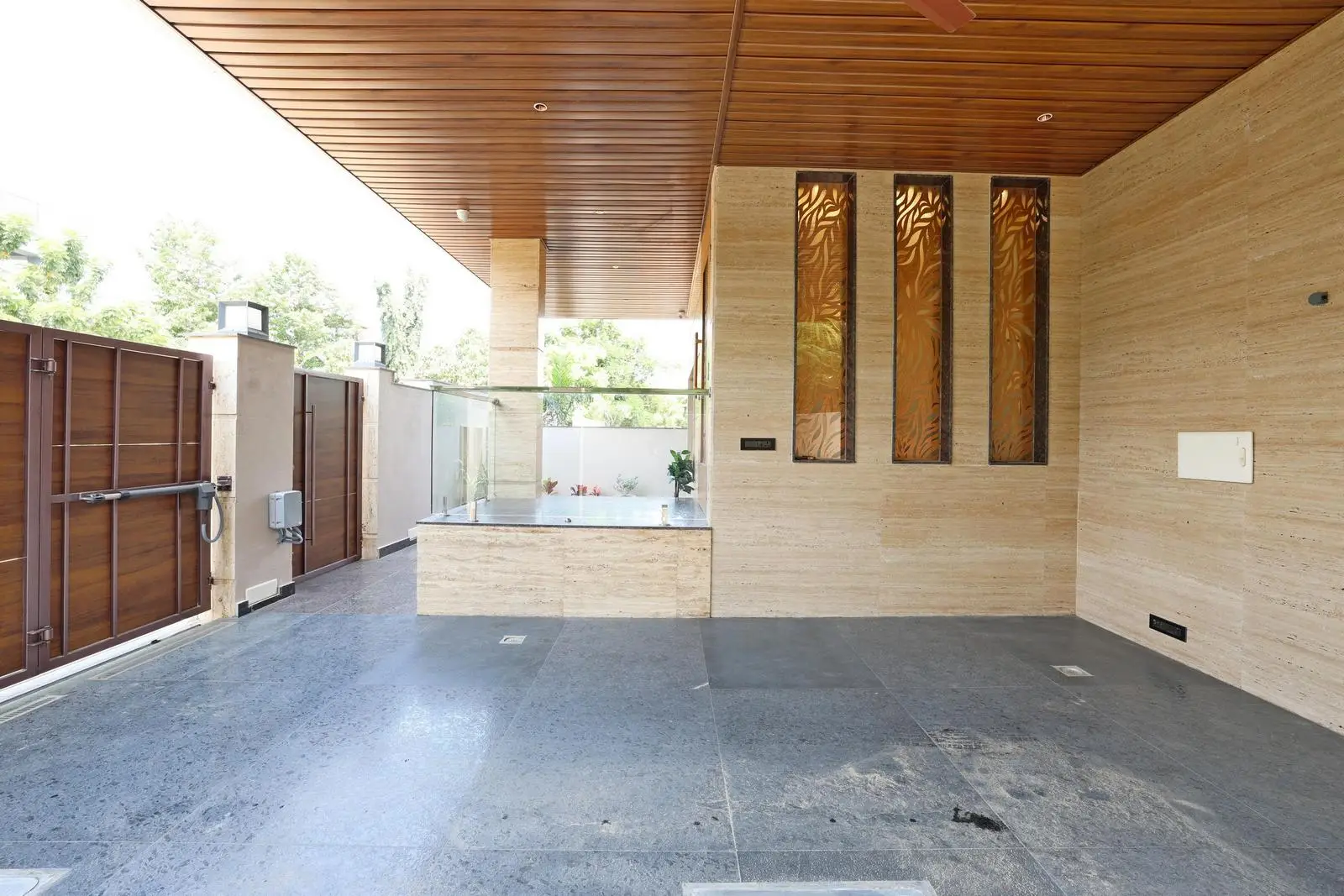 The semi-covered car parking offers protection and openness, with a rectilinear layout for easy access. Integrated walls, gate, and ceiling create a cohesive design, while open boundaries allow natural light and ventilation.