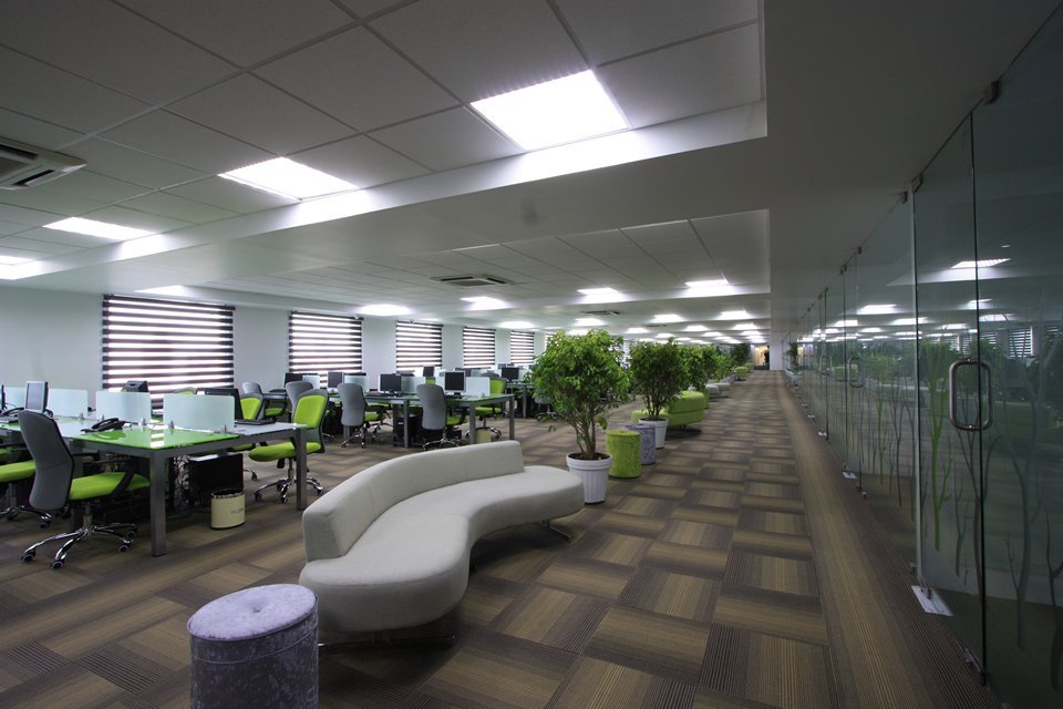 Office with patterned flooring for acoustics, bright white desks, and green accents that add vibrancy and balance professionalism.