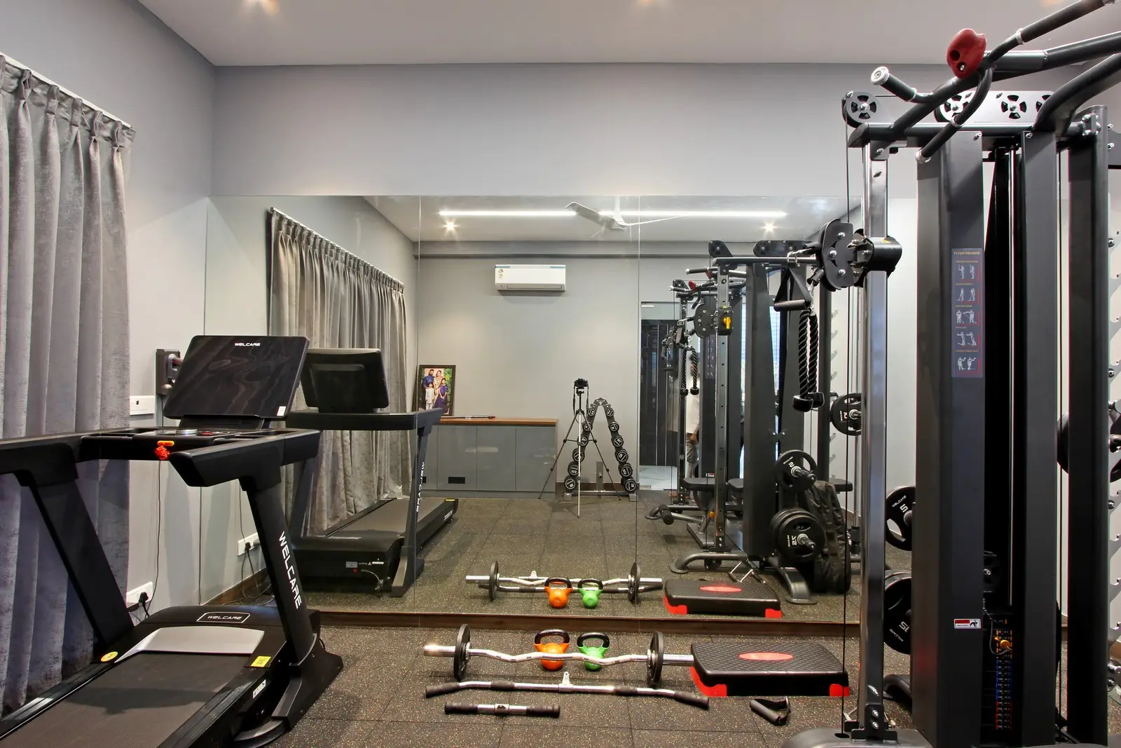 Treadmill, multi-functional cable machine, and organized dumbbells on a textured rubber floor combine sleek design with functionality in the home gym.
