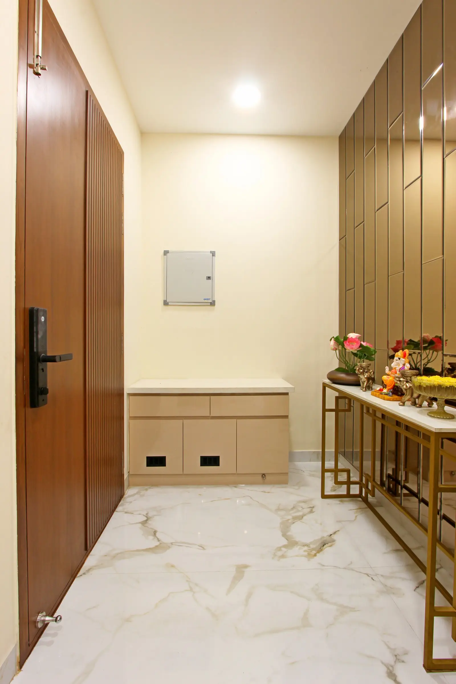 A luxurious foyer featuring marble flooring with golden veining, bronze wall panels, a wooden door, and a gold-framed console table for a refined look.


