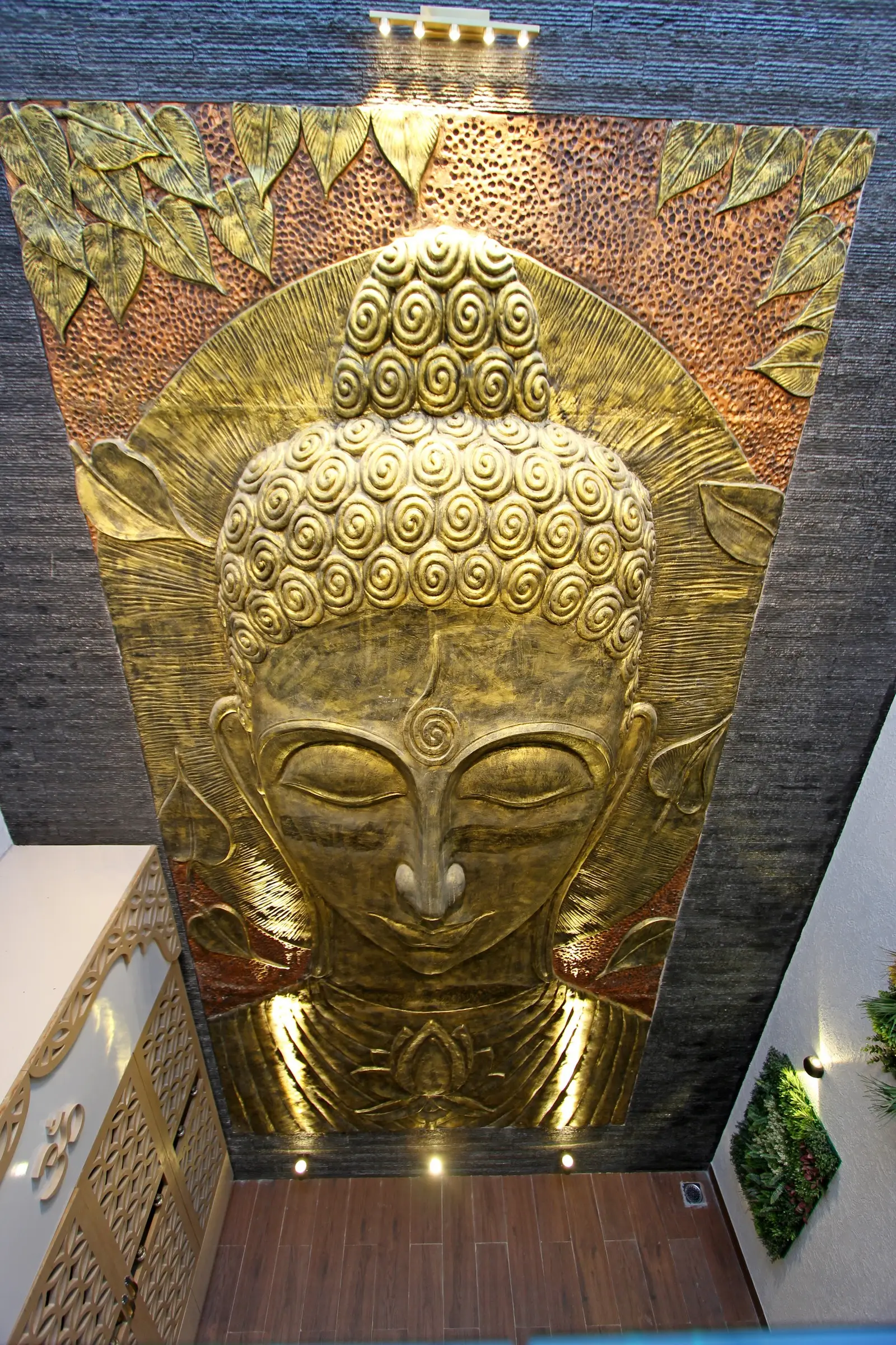 A grand golden Buddha mural against dark stone, warm lighting, and wood flooring inspires peaceful design, spiritual insight, and mindful-home elements.