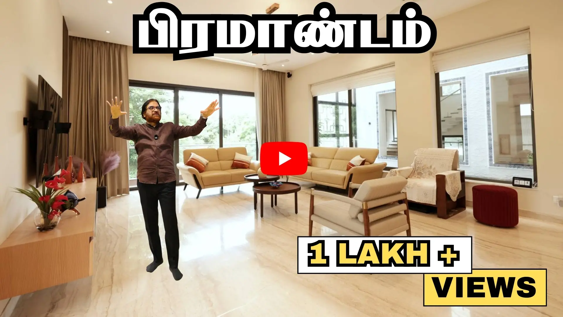 A man standing in a spacious, well-lit living room with beige furniture and large windows; Tamil text at top and English text '1 LAKH+ VIEWS' at bottom right, overlaid with a YouTube play button icon in the center.
