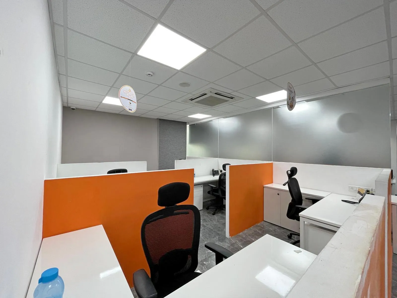 The AVP cubicles feature semi-private workstations with orange accents and ergonomic desks for focused productivity.