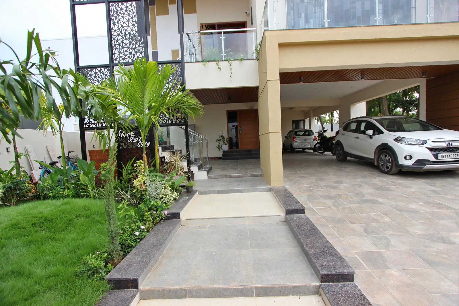 Parking beneath the cantilevered upper floor saves space and provides shade. A verandah, clear driveway, and landscaped strip ensure smooth circulation and a welcoming entrance.