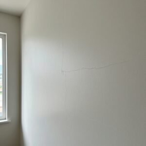 How to Stop Cracks in Your Home: Professional Guidance from Architect Dameem Ansari 2 White interior wall with multiple visible hairline cracks near a window on the left side allowing daylight in.