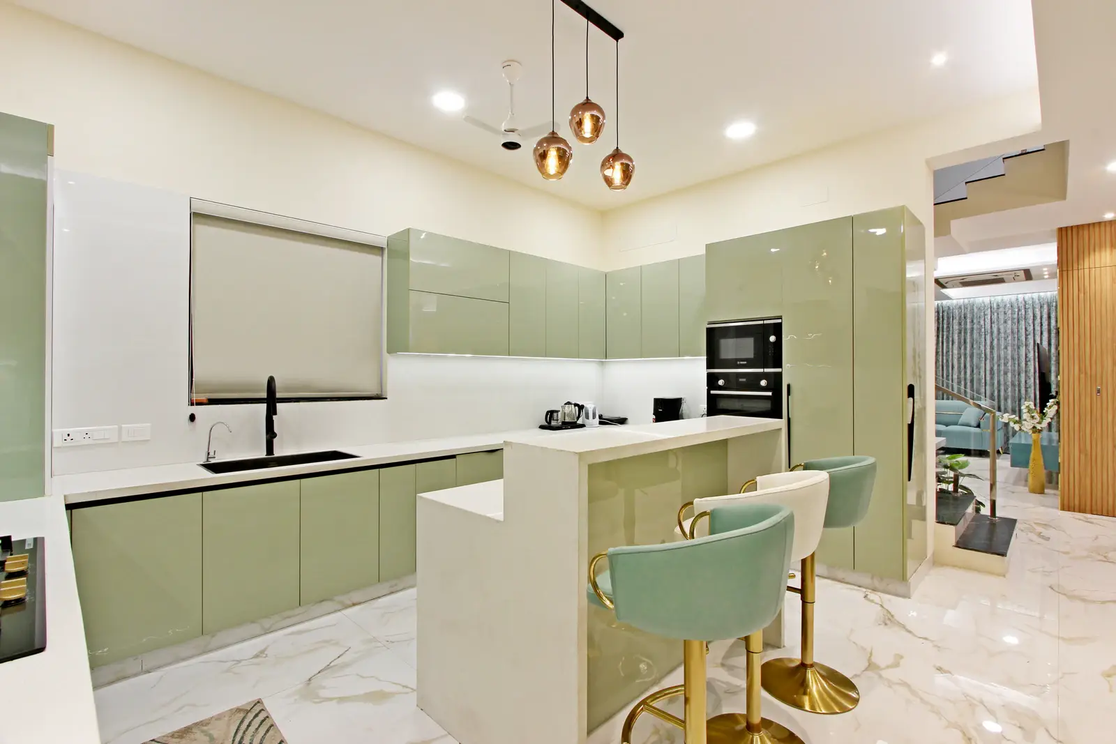 The kitchen displays a modern aesthetic with glossy sage green cabinets, white quartz countertops, an U-shaped layout, and sleek black appliances for enhanced functionality.
