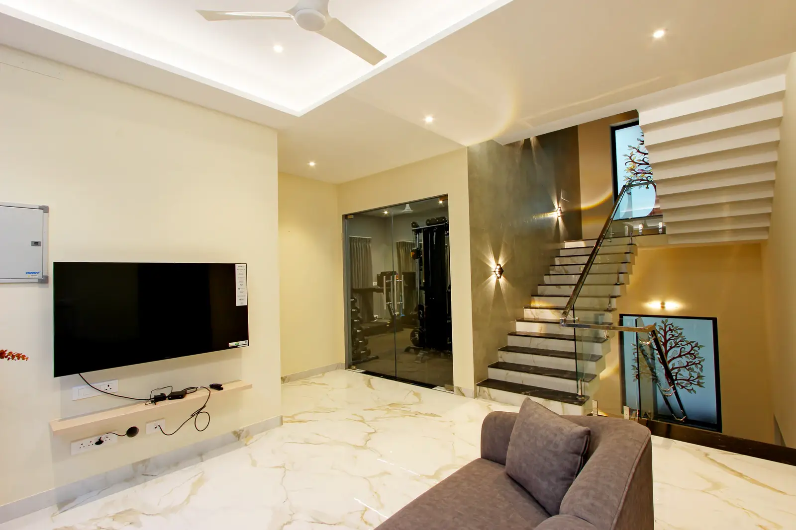 A comfortable grey upholstered sofa faces a wall-mounted flat-screen television, creating a cozy entertainment zone. 