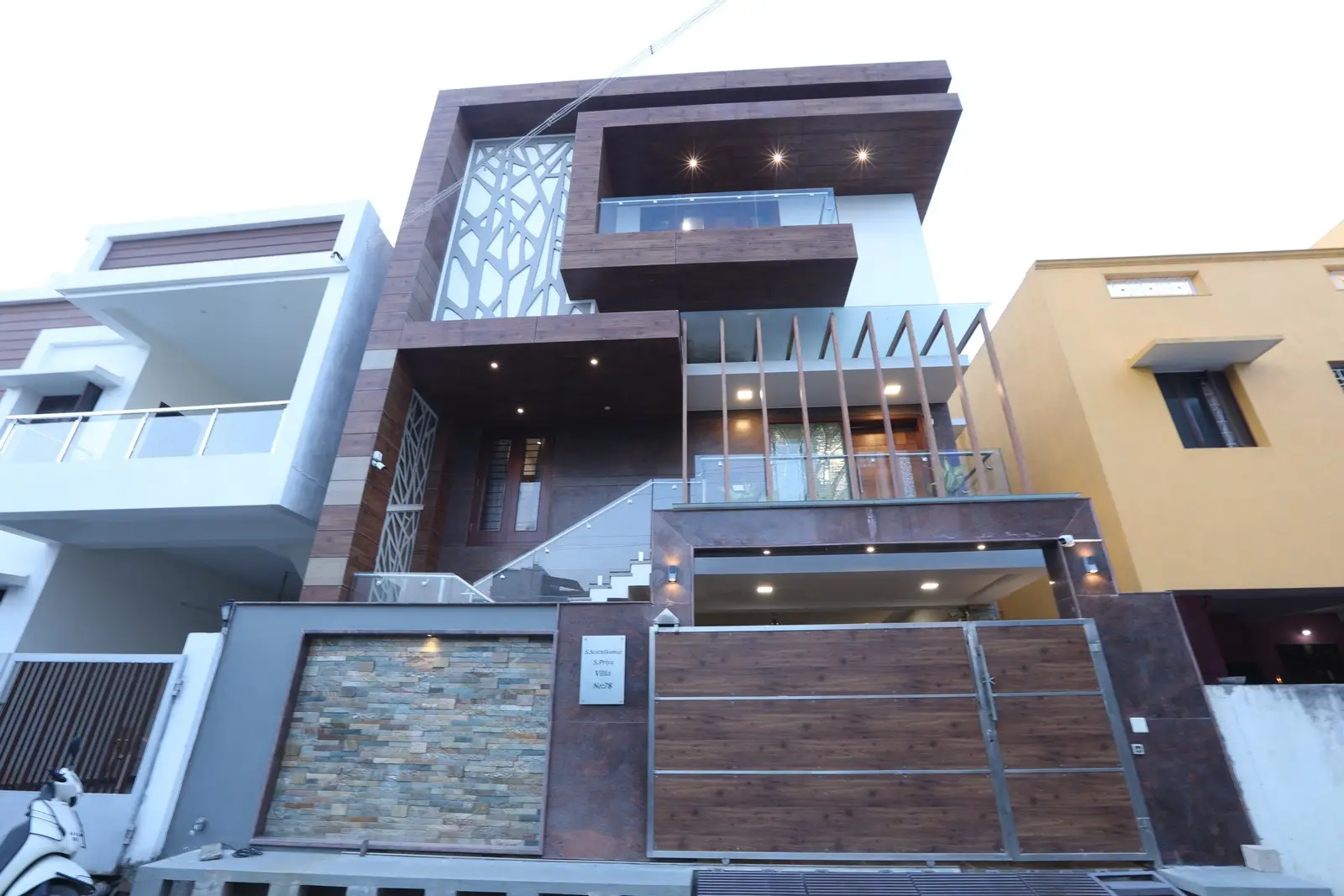 The front elevation features bold vertical and horizontal elements with deep browns, dark beige, red accents, and subtle gold for added luxury.

.