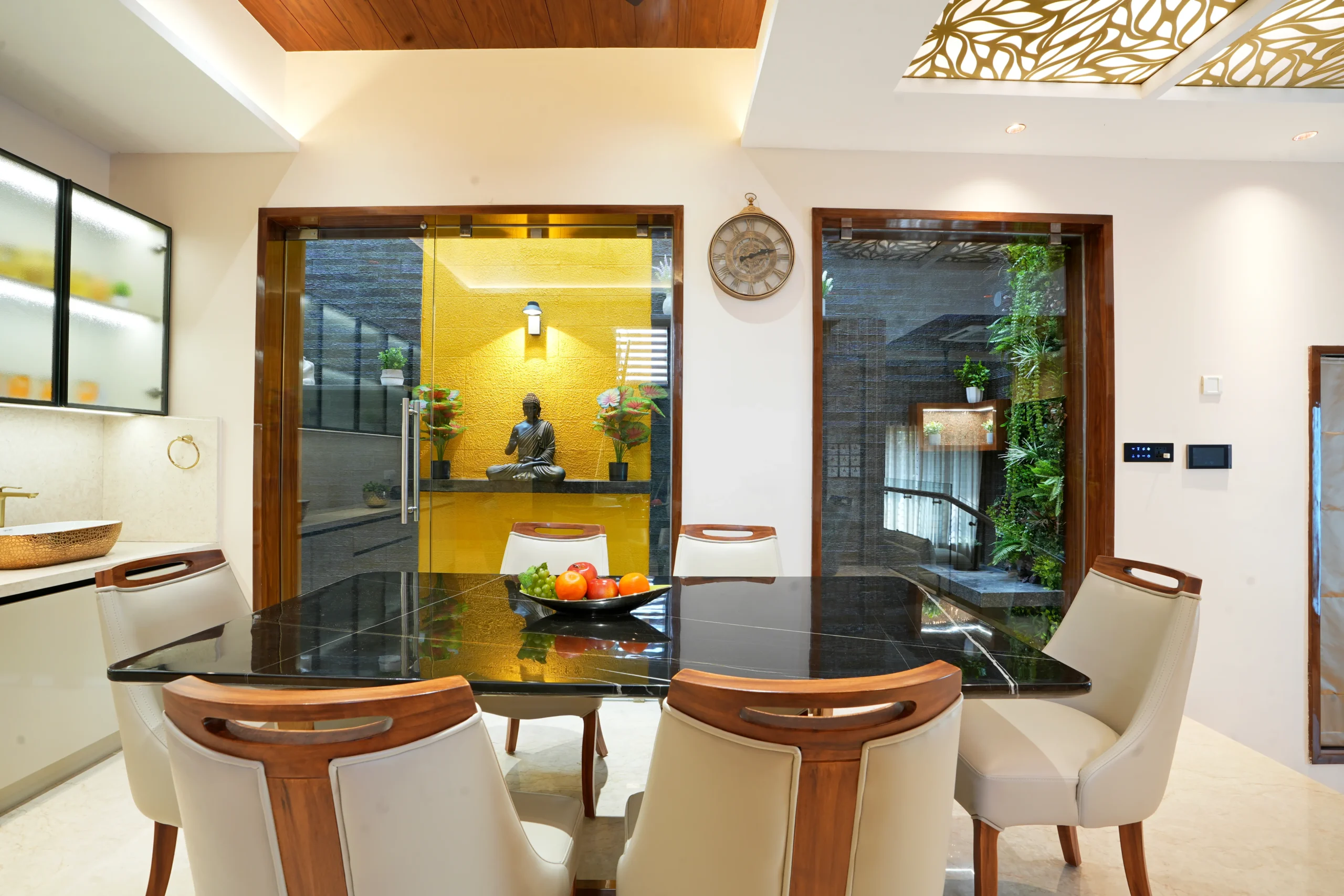 This dining area highlights modern sophistication with a black glass-top table, six cream leather chairs, marble flooring, and a wooden ceiling with recessed lighting.