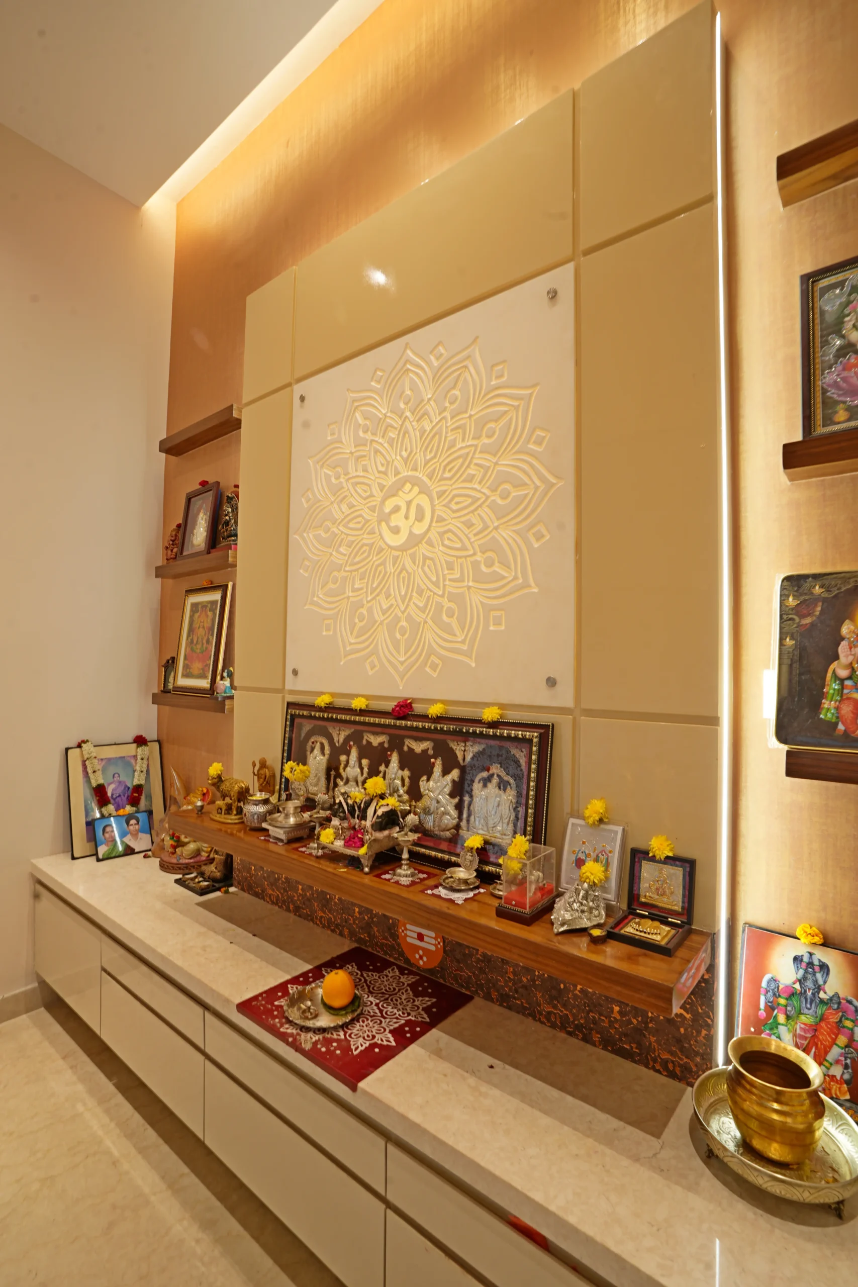 This pooja room showcases a golden mandala backdrop with the sacred “Om” symbol, blending traditional spirituality with modern elegance and warmth.

