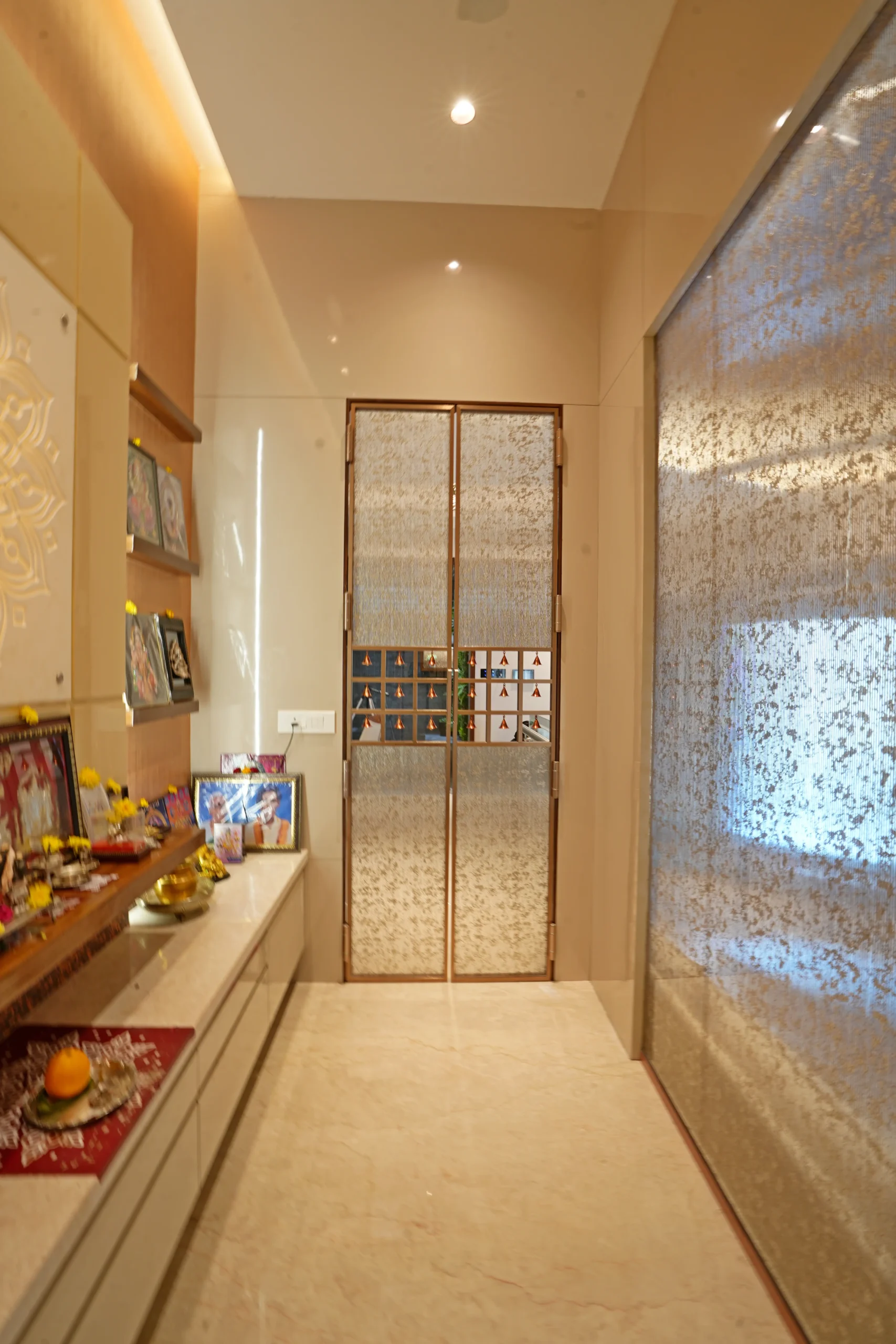 Polished wood, cream marble, and soft recessed lighting enhance the serene ambiance, while floating shelves display idols and artwork beautifully.