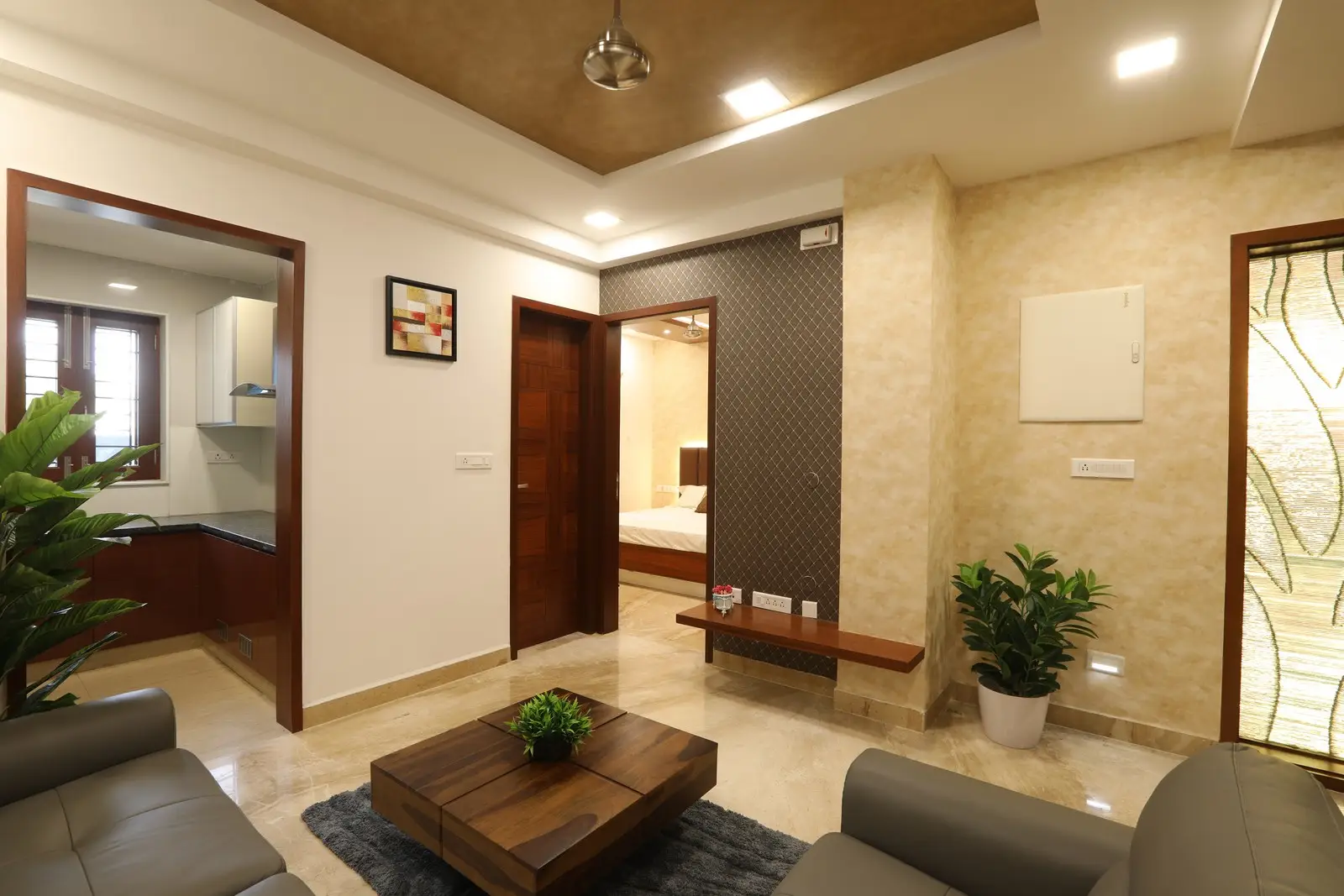 A modern living room featuring grey sofas, a wooden coffee table, recessed lighting, beige flooring, and elegant curtains creating a warm, elegant atmosphere.