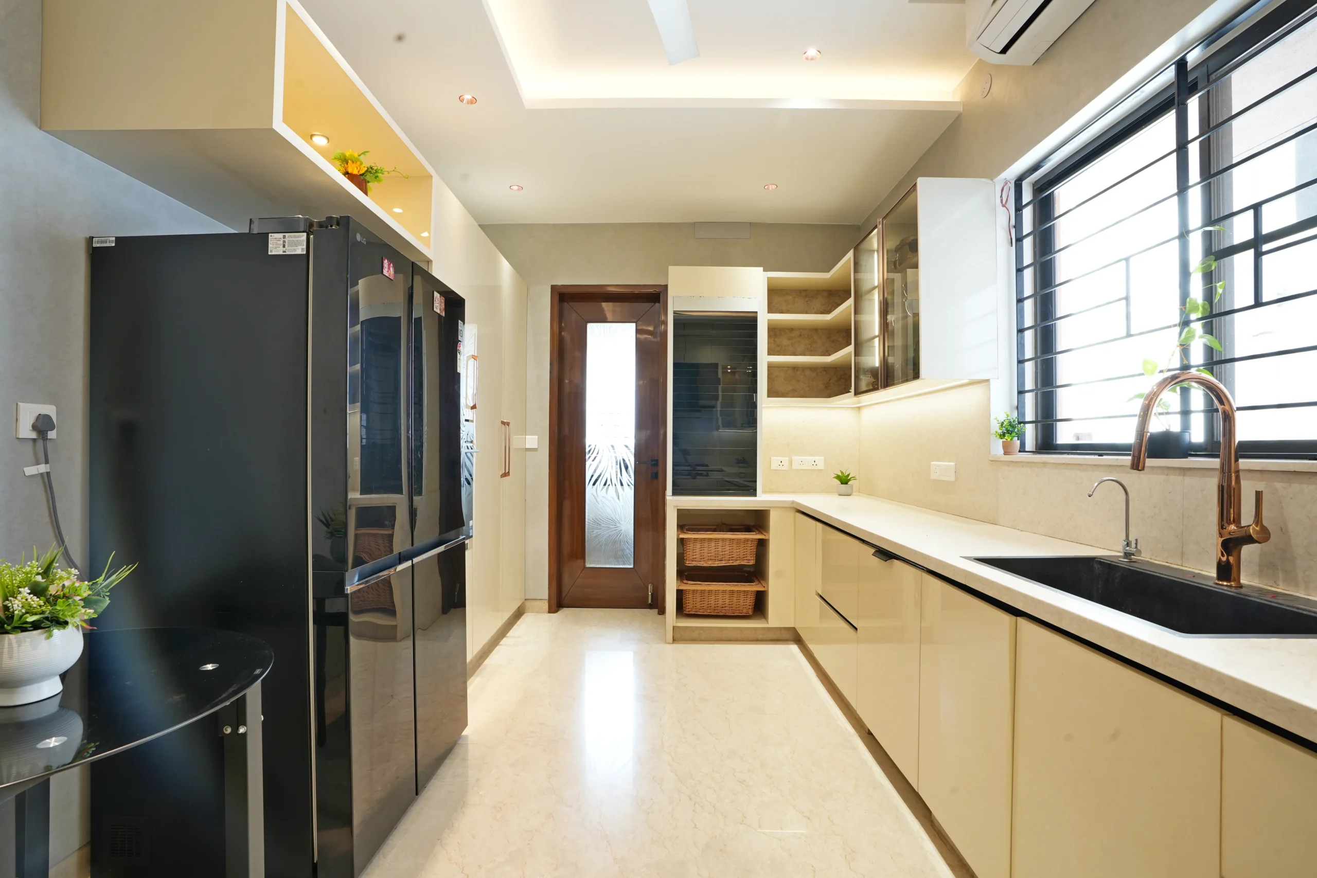 This modern kitchen features glossy beige cabinets, light quartz countertops, and a sleek black refrigerator, creating a refined and functional layout.