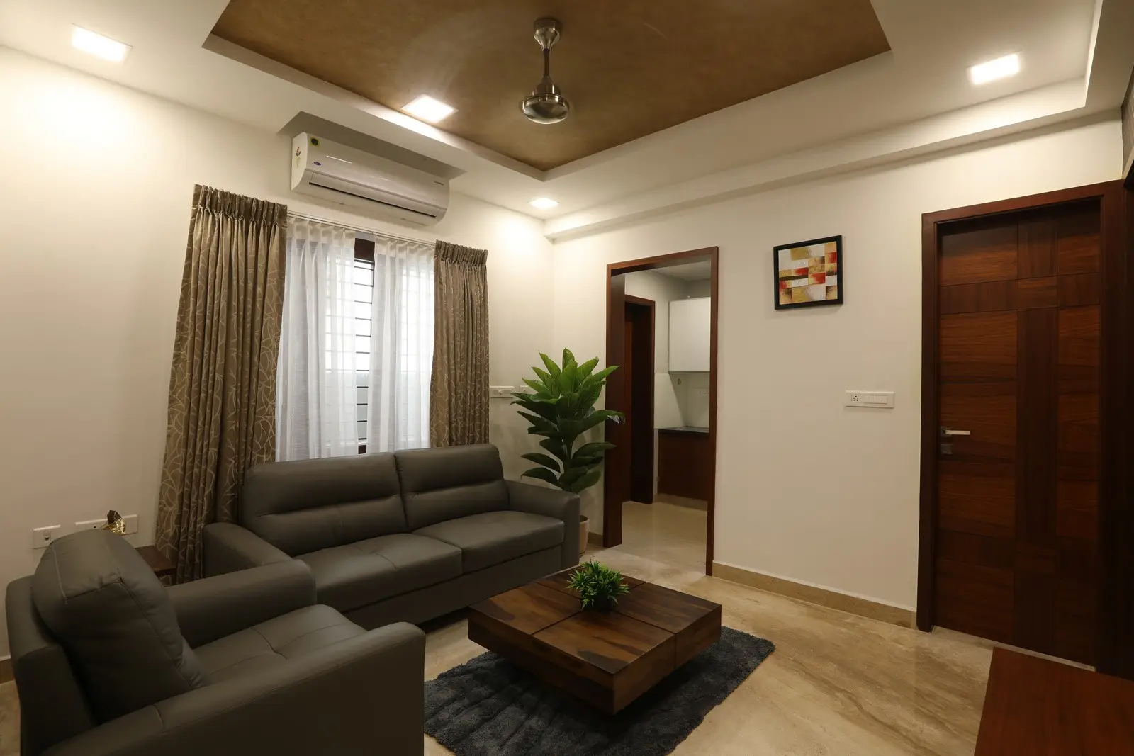 This elegant living room showcases neutral tones, recessed lighting, stylish furniture, indoor plants, and wooden accents, creating a warm, inviting, and sophisticated atmosphere.


