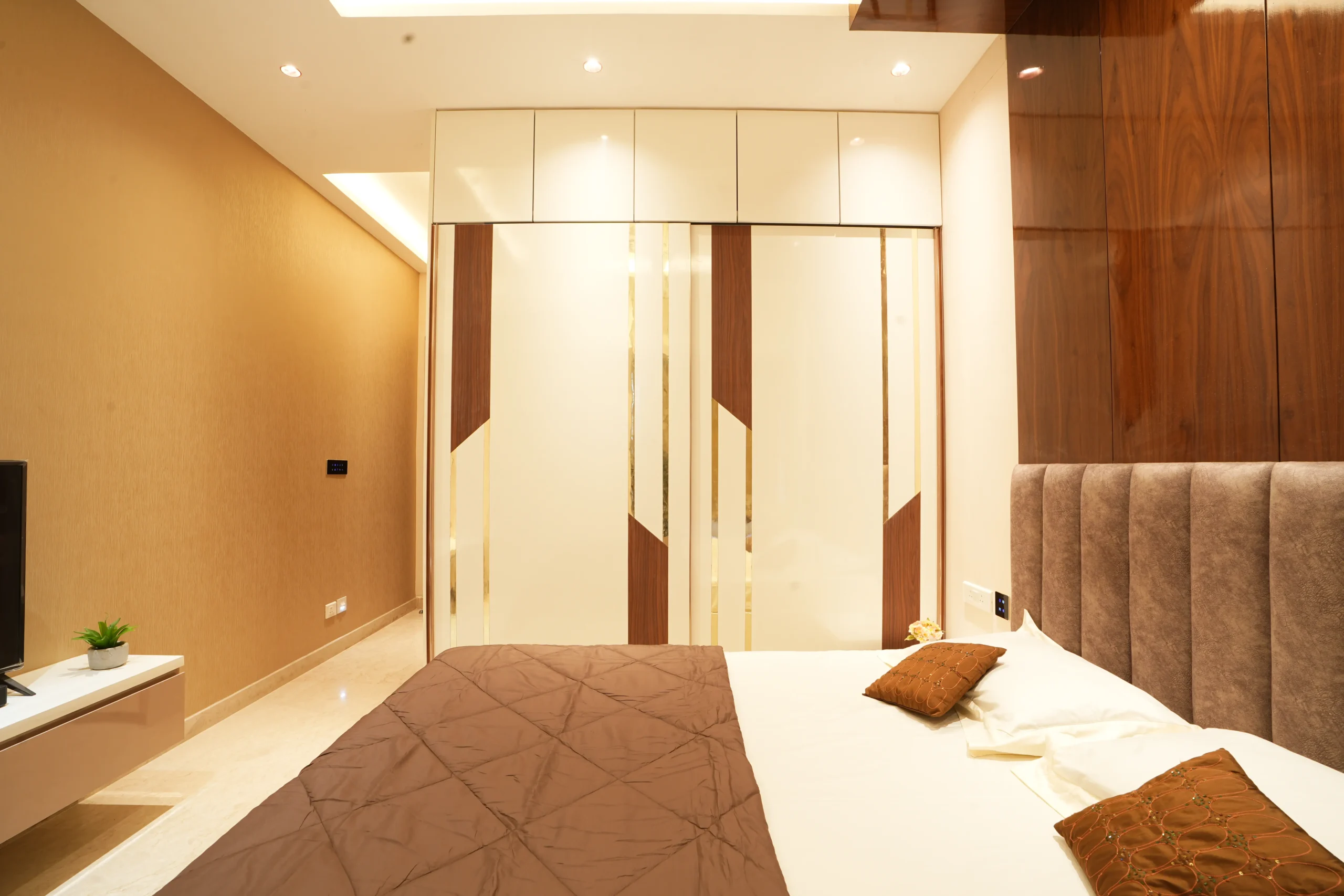 This bedroom features a refined modern design with a warm neutral palette, combining beige tones, wooden accents, and luxurious textures for a calm, elegant atmosphere.