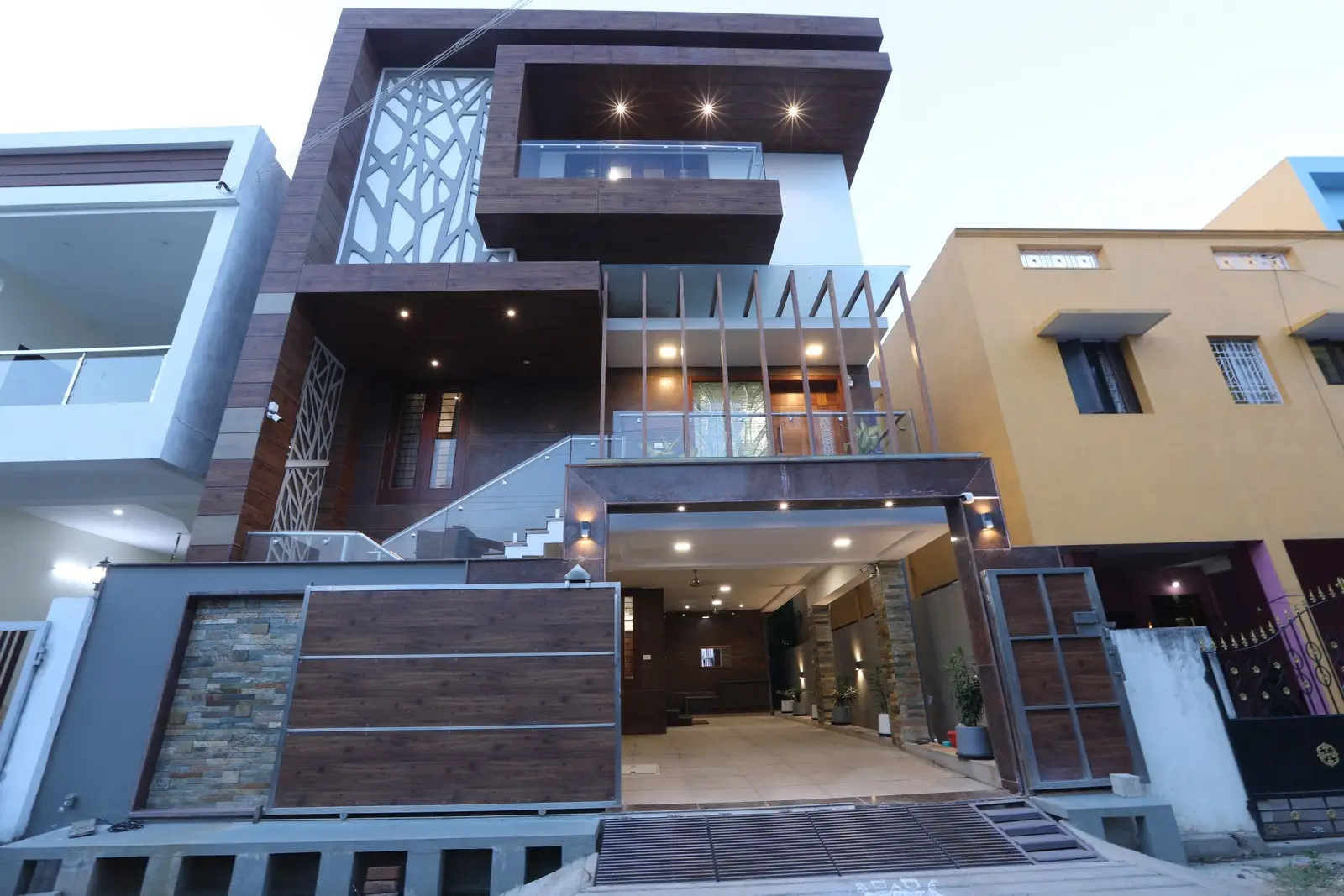 This elegantly designed residence showcases geometric patterns, wooden cladding, glass railings, and ambient lighting, offering a sophisticated and visually captivating architectural aesthetic.