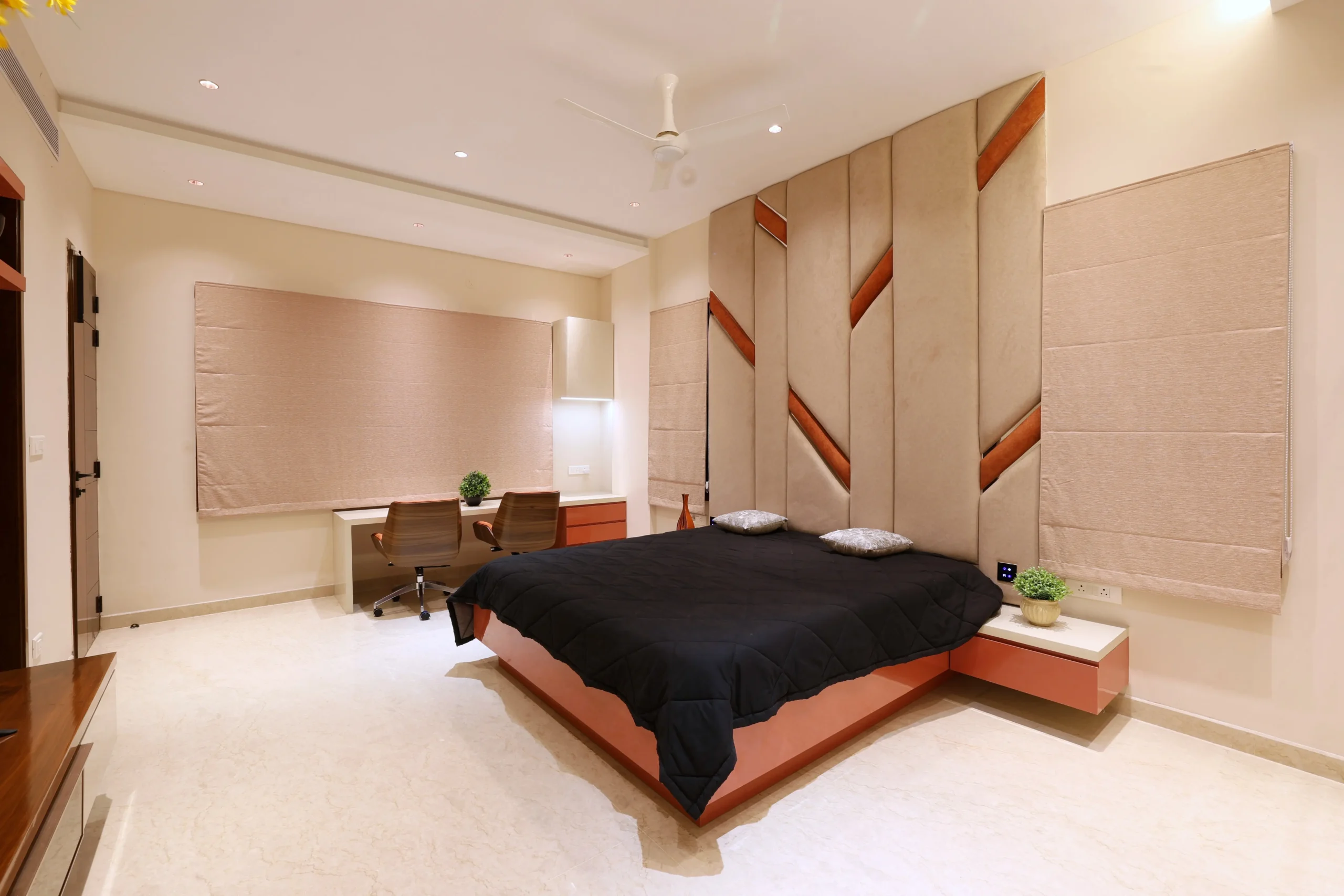 Floating terracotta nightstands, a built-in study with matching drawers, and a glossy beige wardrobe offer functional storage while maintaining a cohesive, contemporary aesthetic throughout the room.