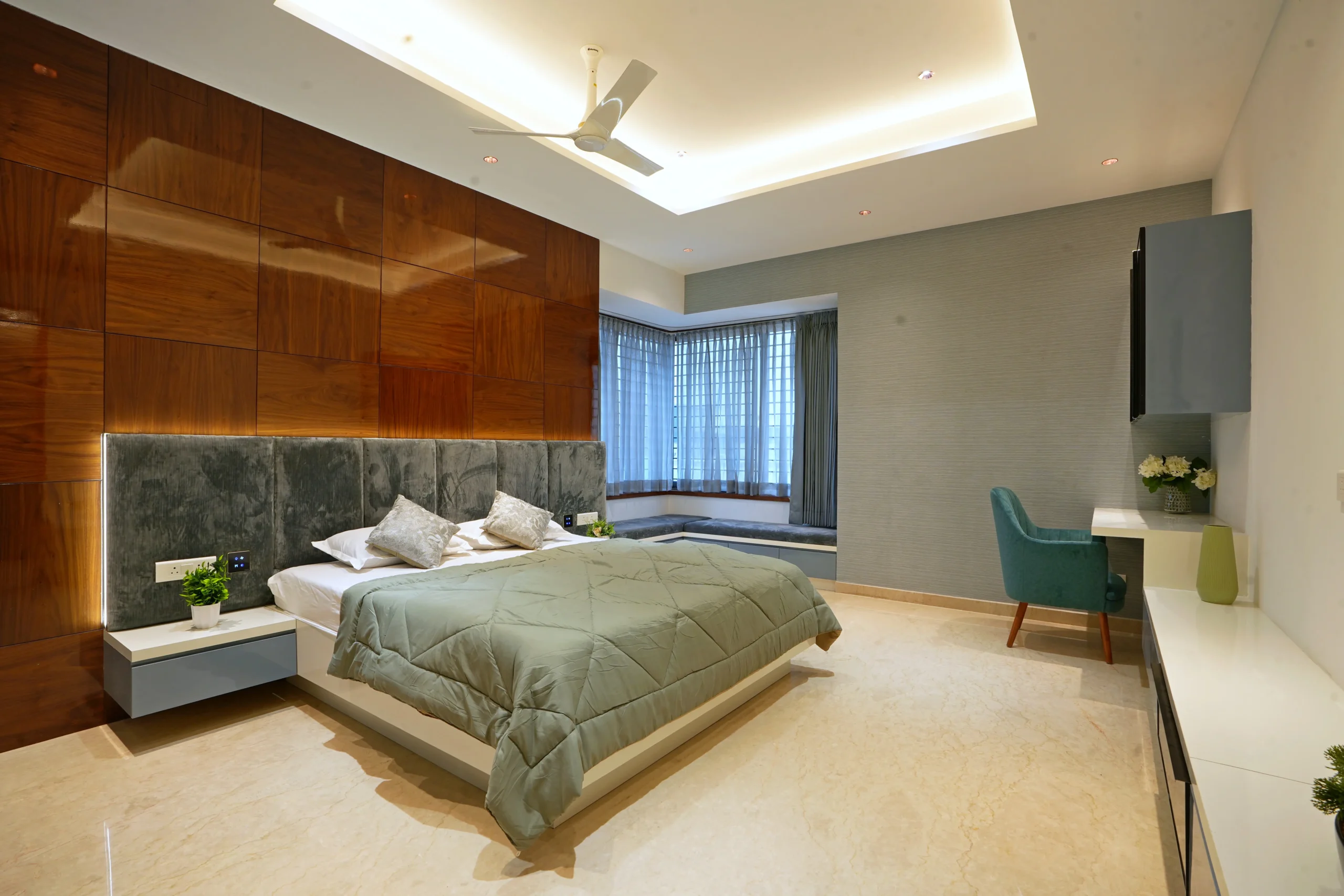 This bedroom features a refined modern design with muted greys, warm woods, and soft neutrals. The walnut feature wall and upholstered grey headboard create elegance.