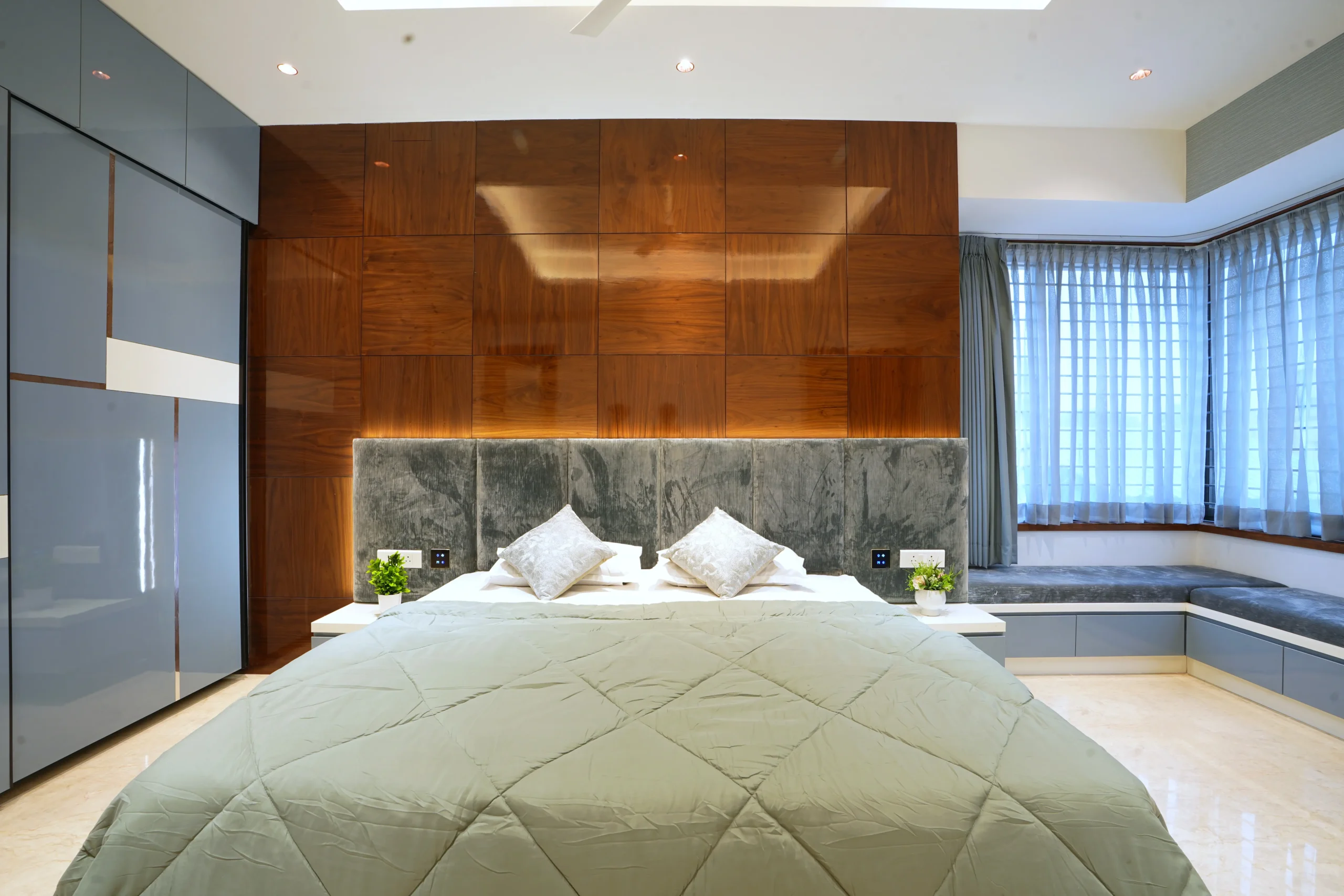 Floating bedside tables, a polished marble floor, built-in window seating, and ample natural light enhance functionality, comfort, and a serene, spacious atmosphere.