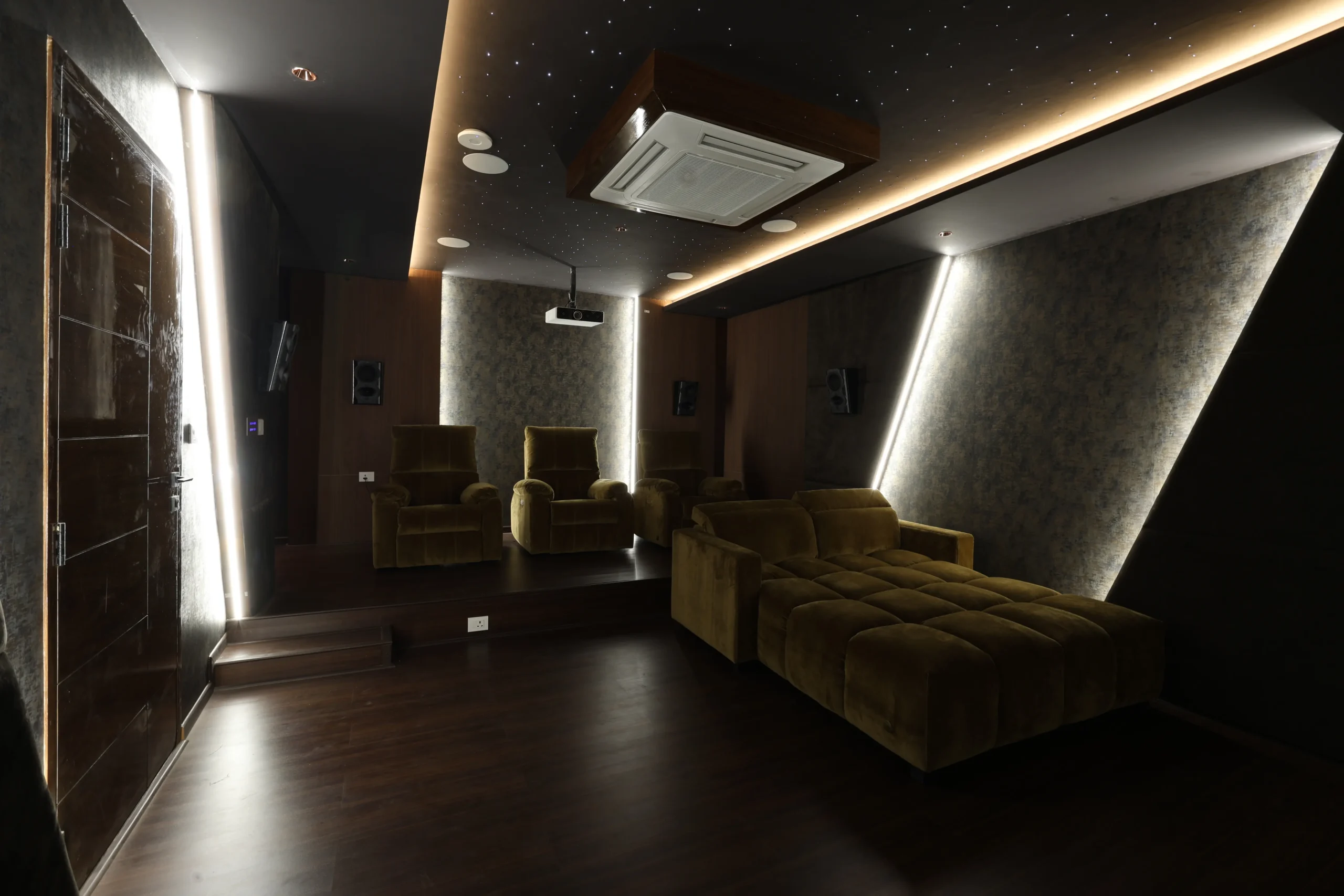 A luxurious home theatre features dark hardwood flooring, textured acoustic walls, starry-sky ceiling, recessed and cove lighting, and a high-definition projector for immersive cinematic experience.